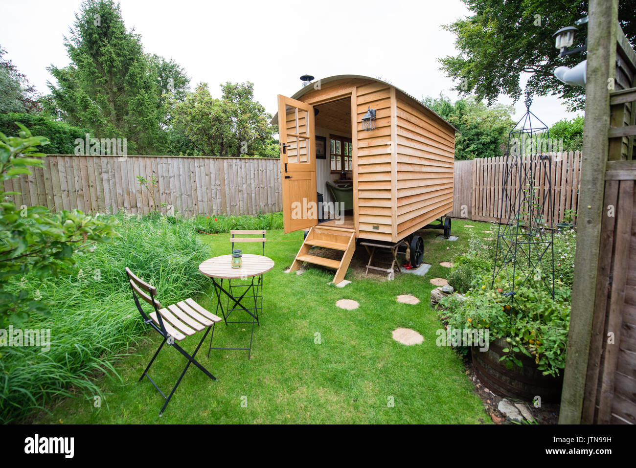 Fabricado a mano de madera cabaña de pastores en una zona rural de jardín con mesa y sillas preparado para huéspedes que buscan vacaciones acogedor glamping en Suffolk, Reino Unido Foto de stock