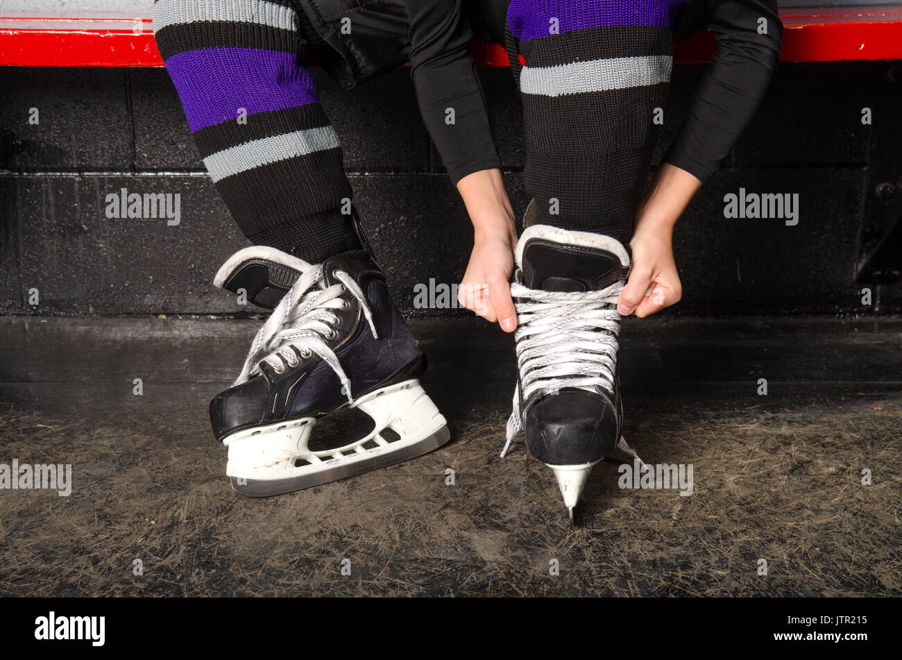 Un niño lazos hockey patines en arena vestidor Foto de stock