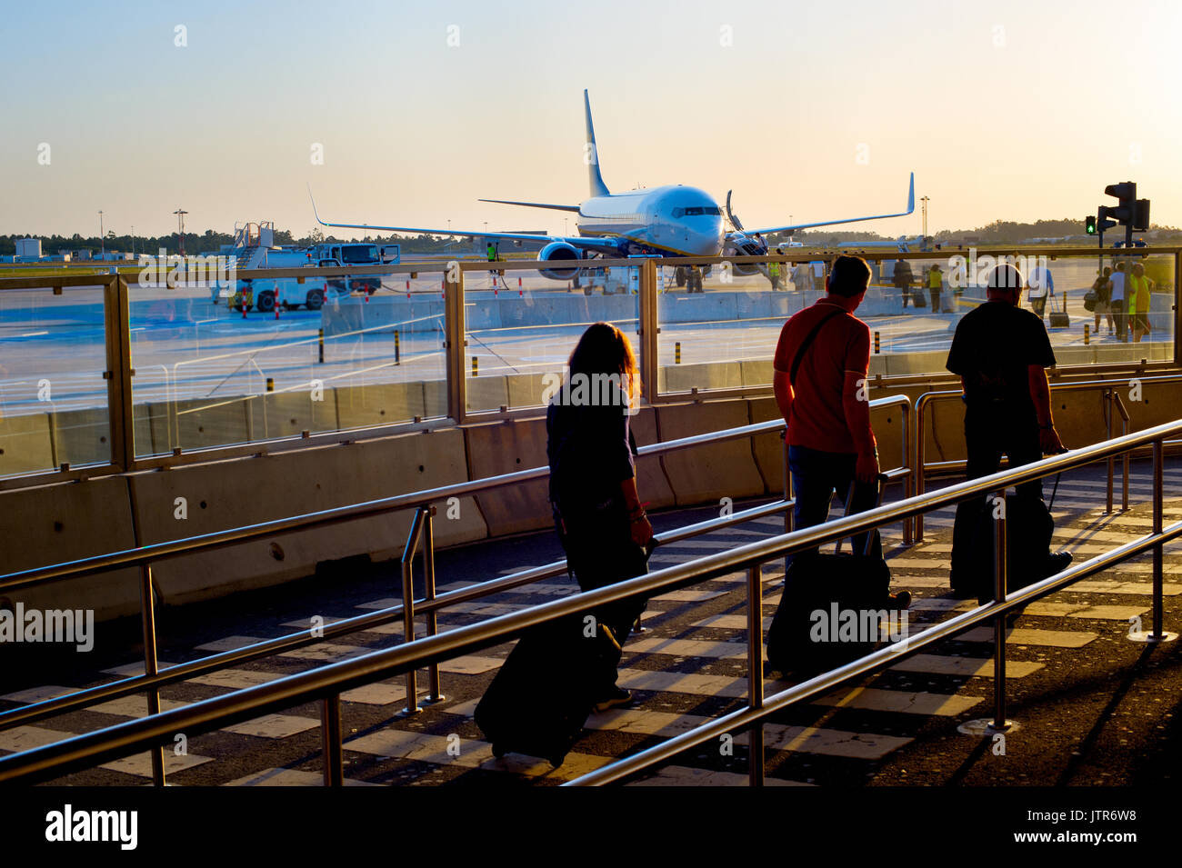 Los pasajeros de avión en un aeropuerto de embarque al atardecer Foto de stock
