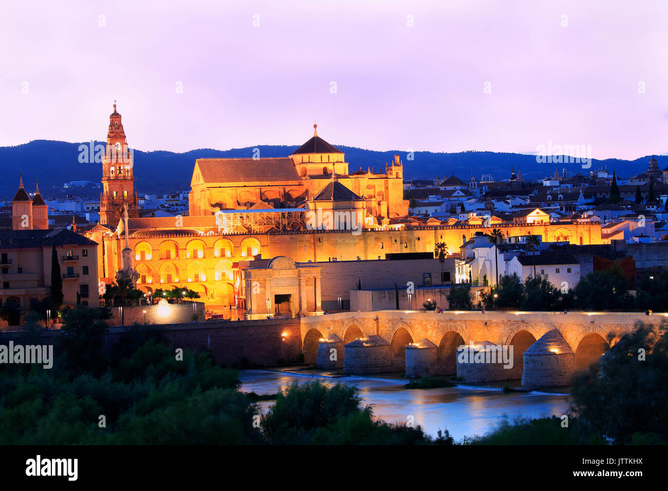Puente Romano y el río Guadalquivir iluminado al atardecer, la Gran Mezquita de Córdoba, España Foto de stock