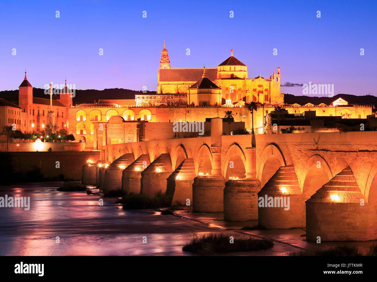 Puente Romano y el río Guadalquivir iluminado al atardecer, la Gran Mezquita de Córdoba, España Foto de stock