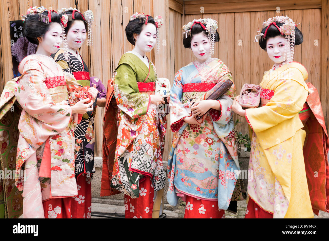 Cinco Geisha en impresionantes kimonos, posando para las fotos, en una calle tradicional de Kyoto en Japón Foto de stock