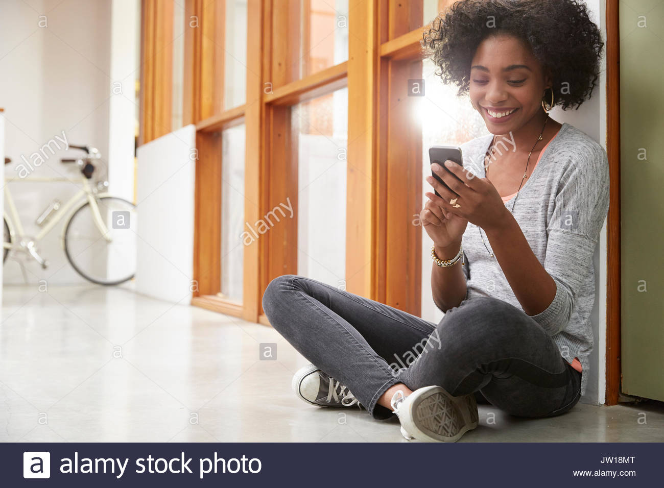 Estudiante universitario americano africano texting con teléfono celular en el corredor Foto de stock