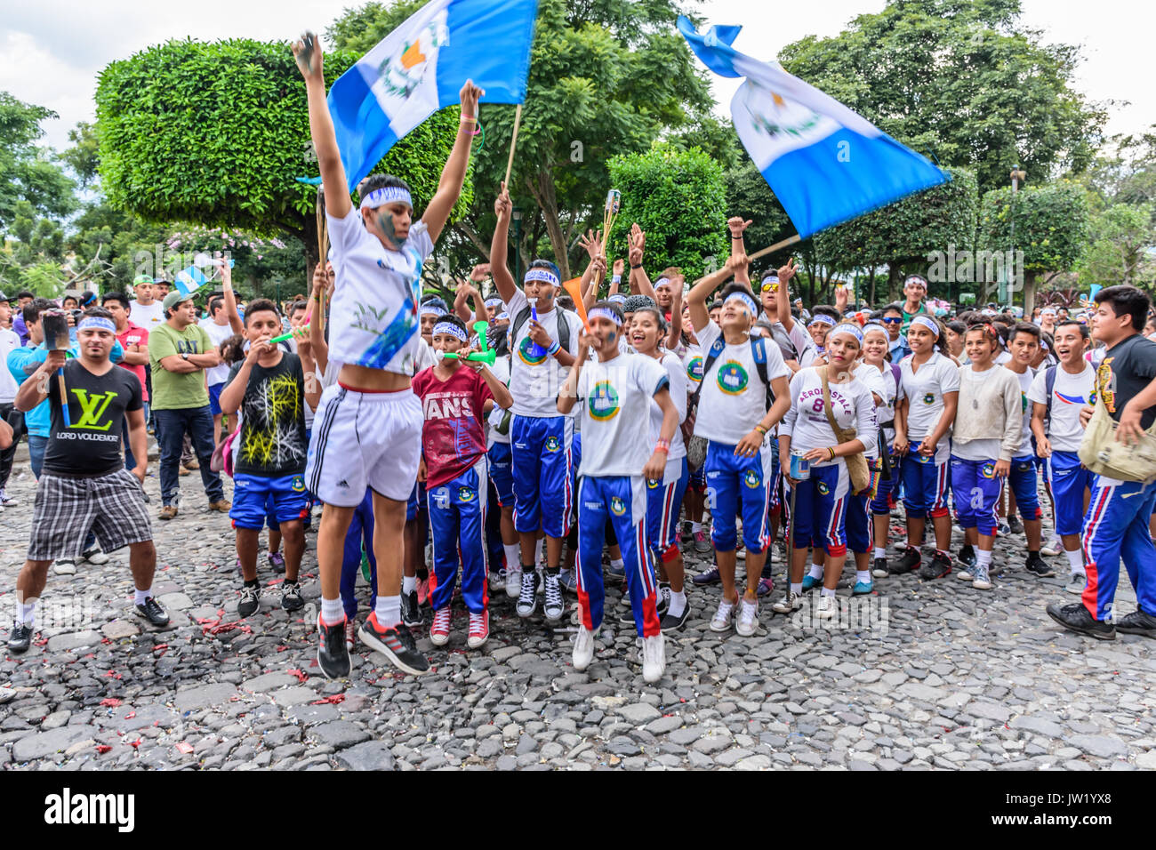 Antigua, Guatemala - Septiembre 14, 2015: los estudiantes se ejecutan con banderas de Guatemala y antorchas encendidas y soplar pitos y cuernos en el día de la independencia de Guatemala Foto de stock