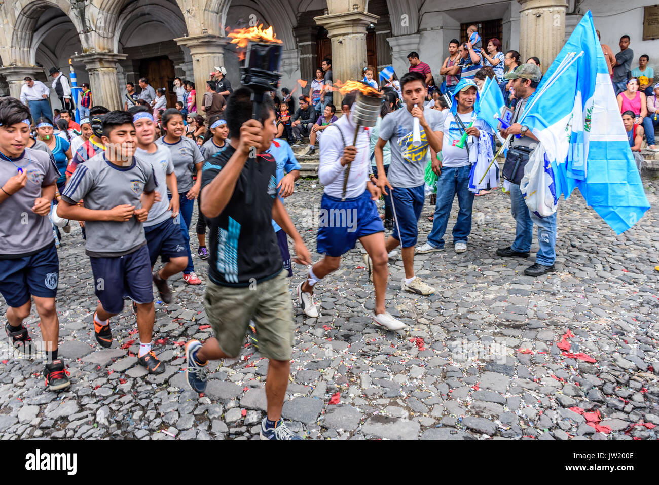 Antigua, Guatemala - Septiembre 14, 2015: los lugareños se ejecutan con banderas de Guatemala y antorchas encendidas y soplar pitos y cuernos durante el día de la independencia de Guatemala Foto de stock