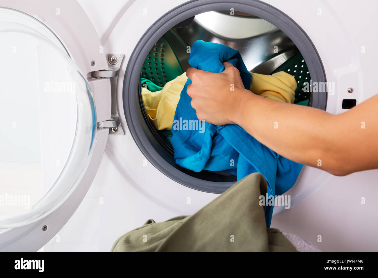 Close-up de mano cargando la ropa sucia en la lavadora Fotografía de stock - Alamy