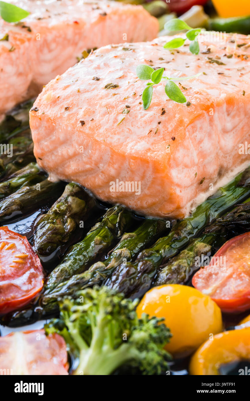 Dos trozos de filete de salmón al horno sobre espárragos verdes, pimiento,  tomates cherry y brócoli en la bandeja para hornear forrada con tomillo  fresco. Almuerzo preparado Fotografía de stock - Alamy