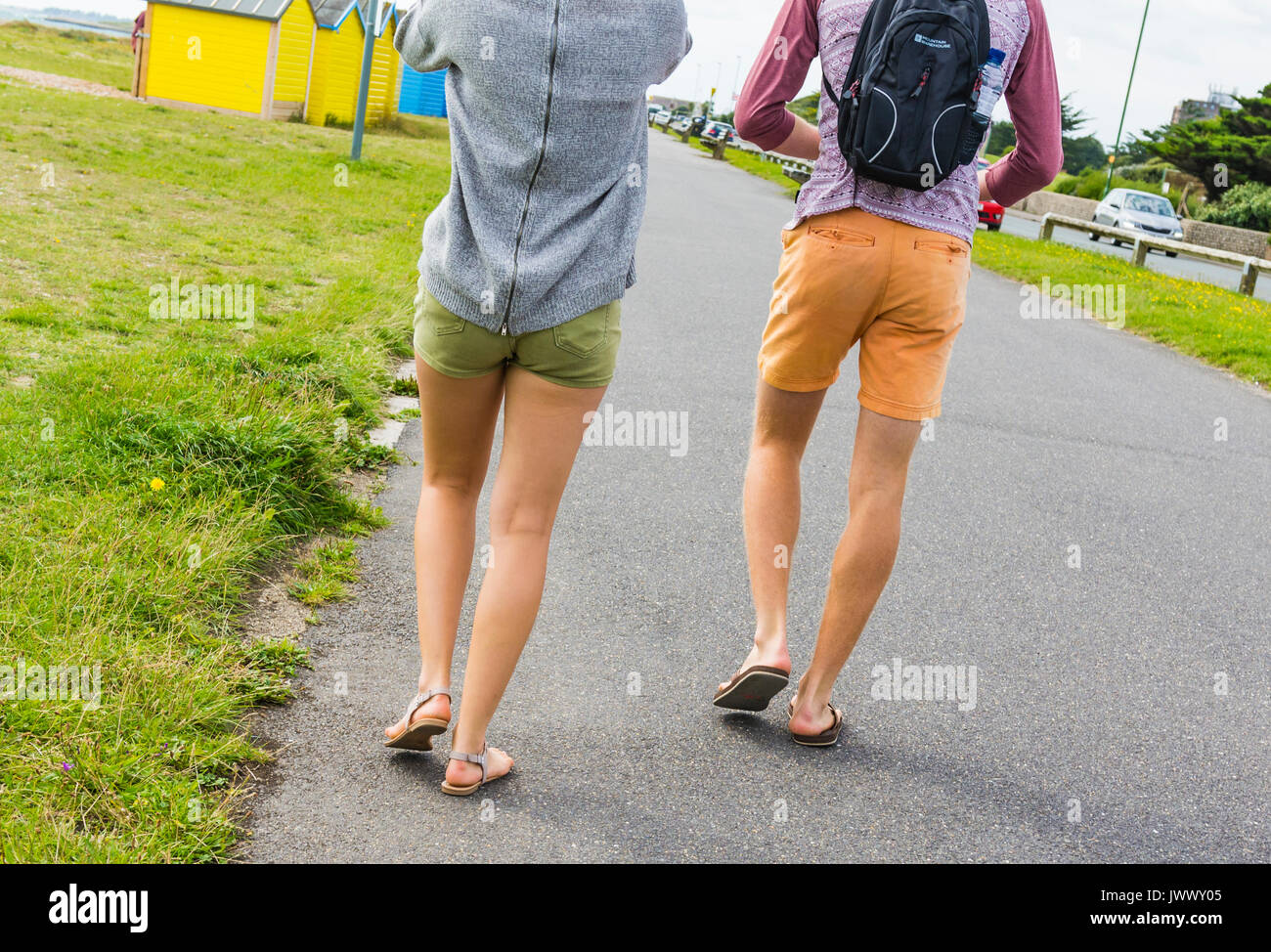 Una joven pareja caminando por el paseo que vistan pantalones cortos, mostrando sólo sus piernas desnudas. Foto de stock
