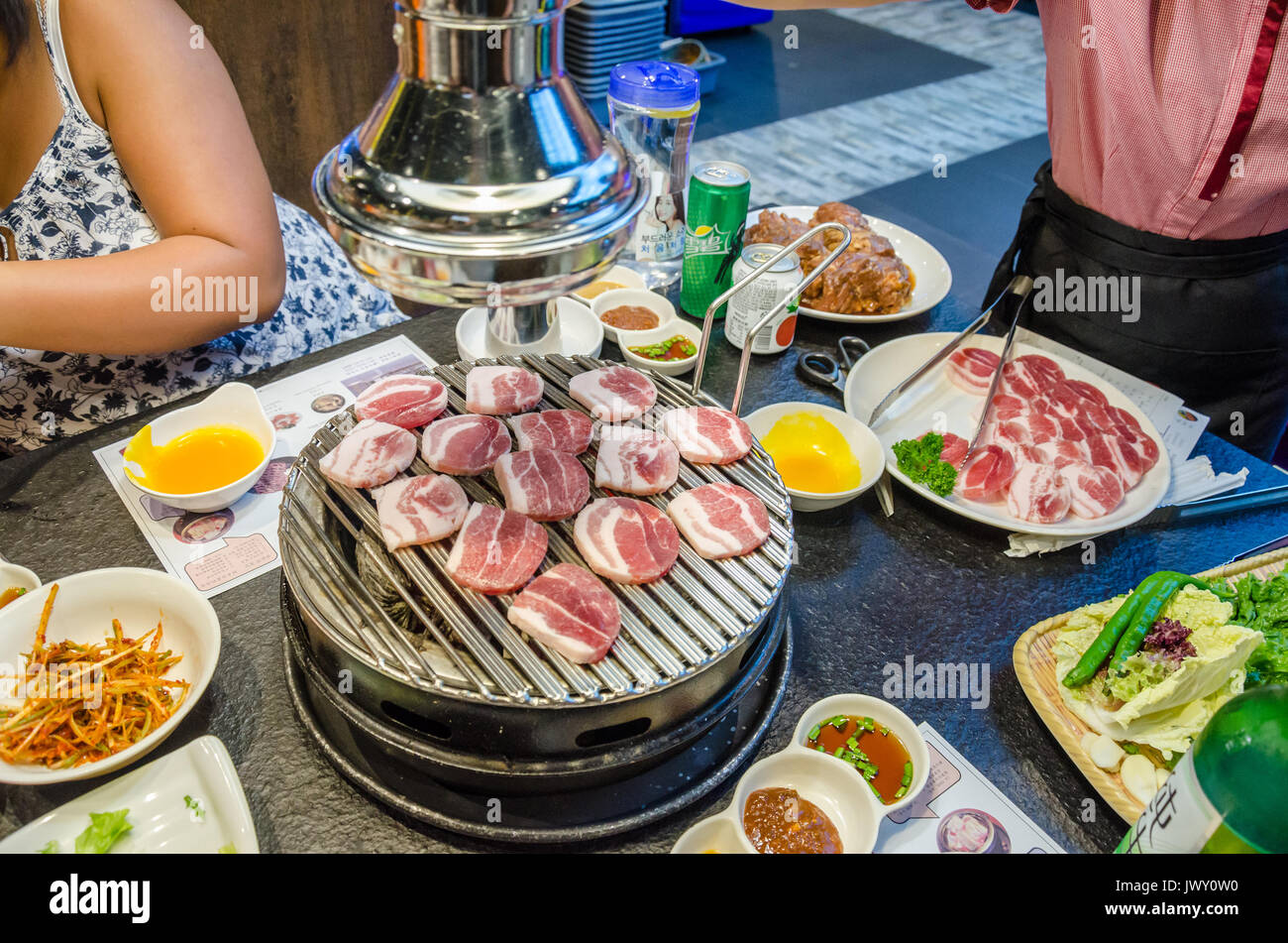 Cocinar la carne en una barbacoa coreana en un restaurante Koream. La  comida se cocina a la parrilla en la mesa delante de los invitados  Fotografía de stock - Alamy