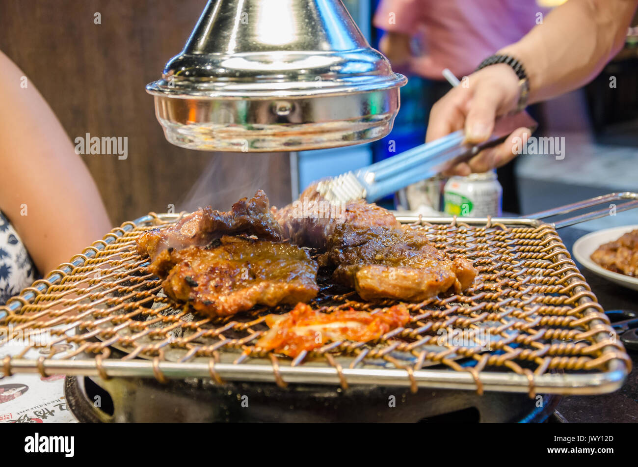 Cocinar la carne en una barbacoa coreana en un restaurante Koream. La  comida se cocina a la parrilla en la mesa delante de los invitados  Fotografía de stock - Alamy