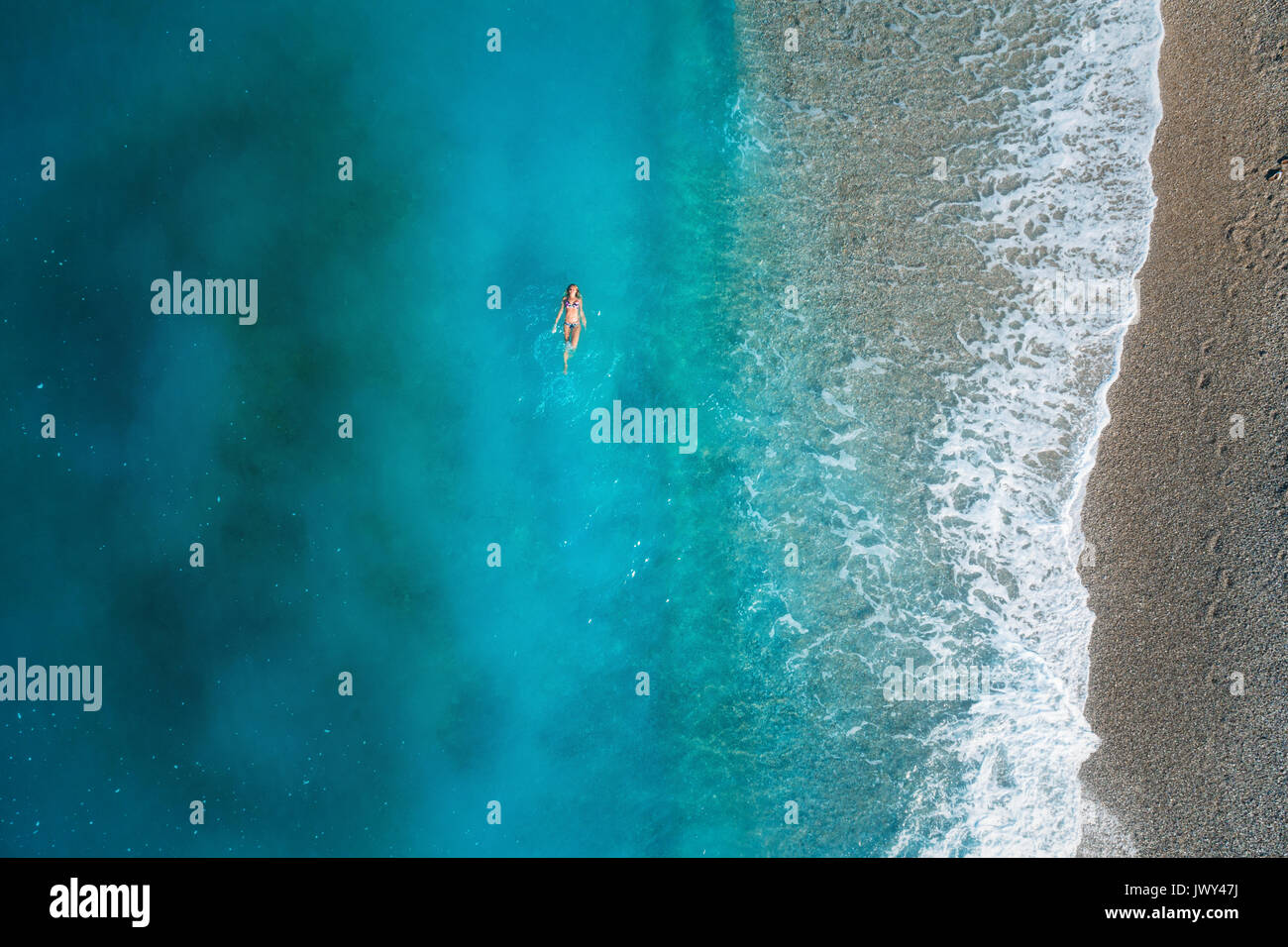 Vista aérea de la mujer nadar en el mar mediterráneo en Oludeniz, Turquía. Hermoso paisaje de verano con la niña, aguas azul claro, olas y arena Foto de stock