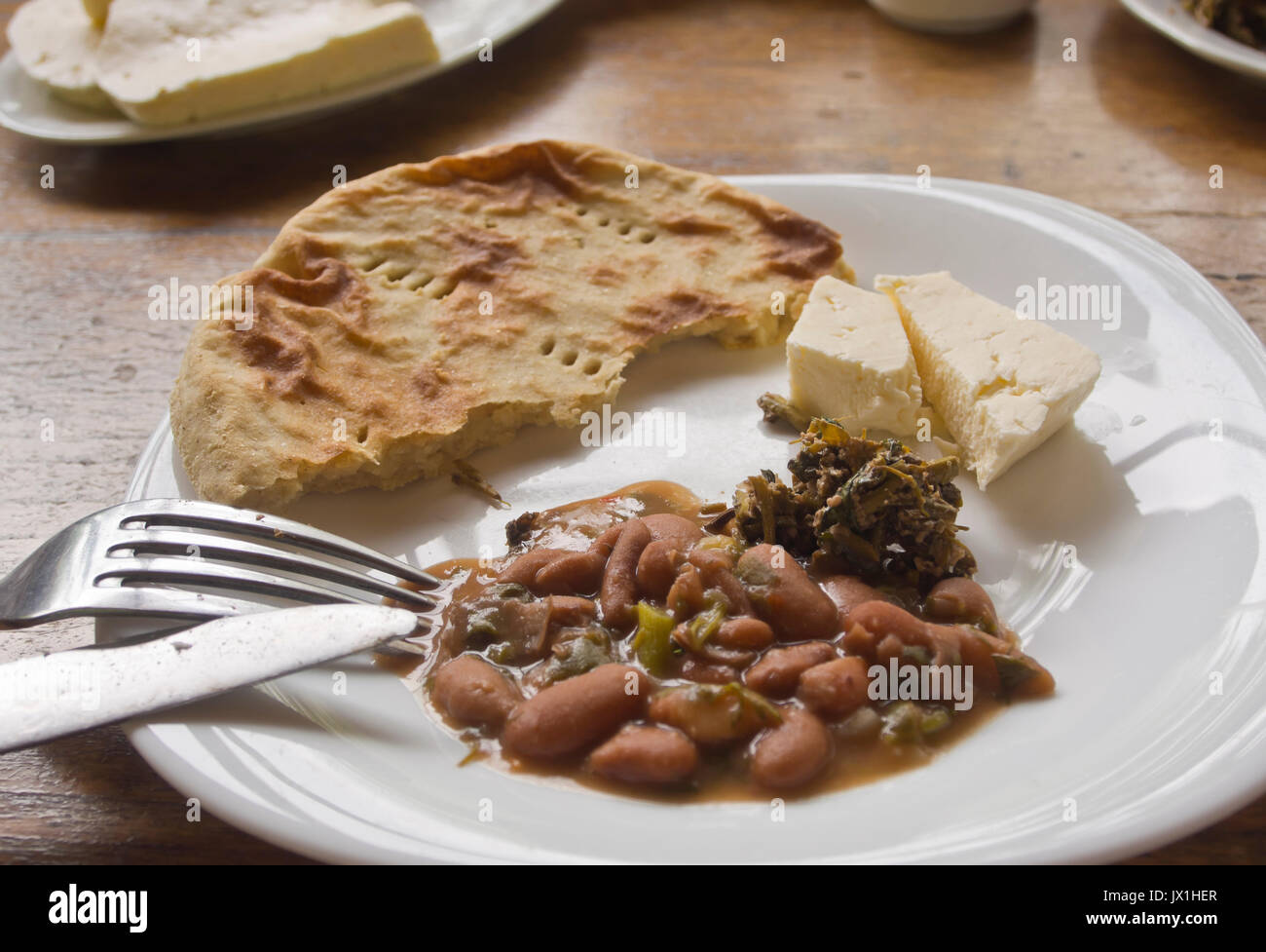 Un guiso de habichuelas marrón con queso local y pan, arrancadores en un restaurante presenta platos de Georgia para los turistas en el camino a través del Cáucaso Foto de stock