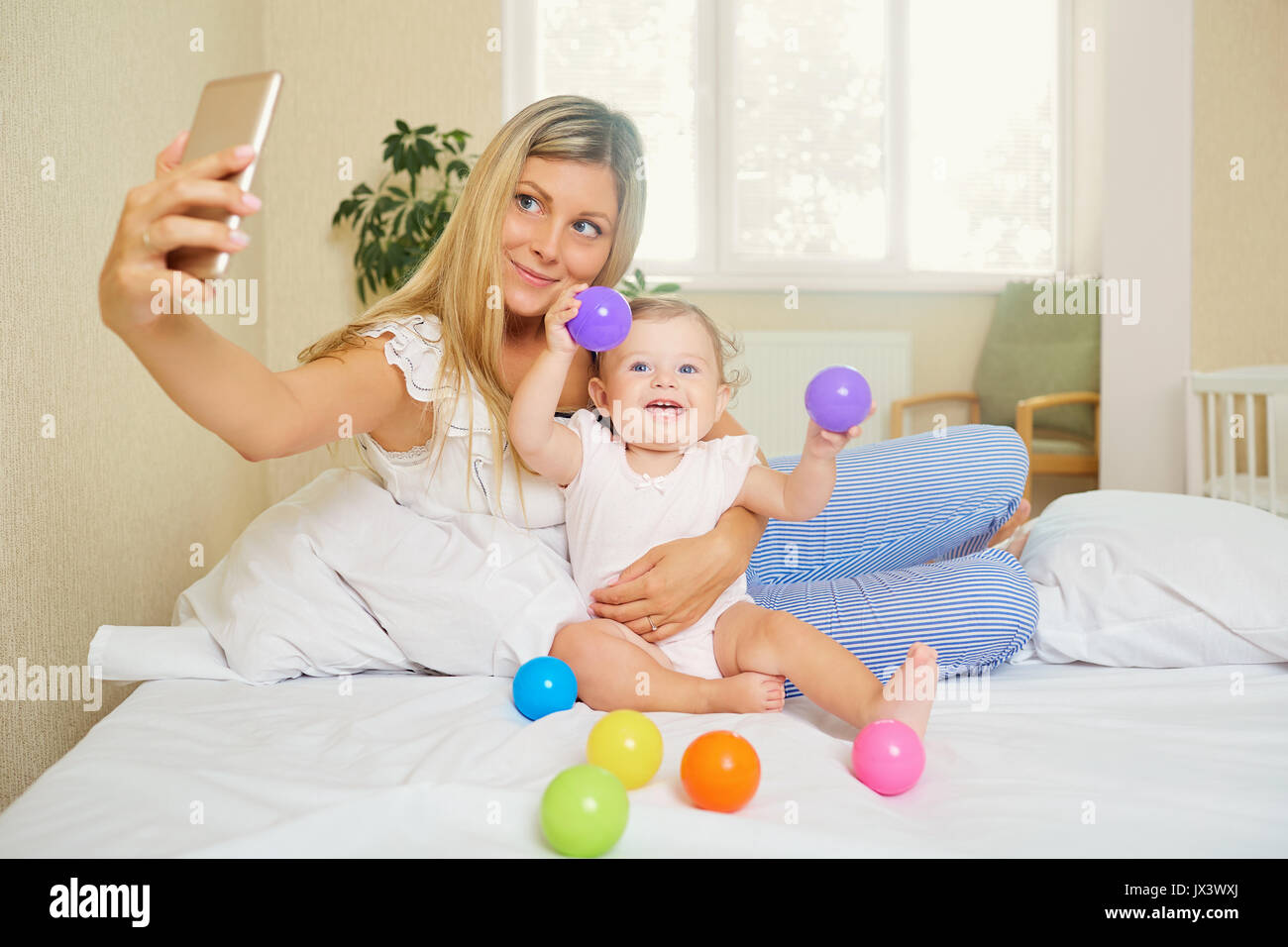 Mamá hace una foto en el teléfono con el bebé en la habitación. Salfie Foto de stock