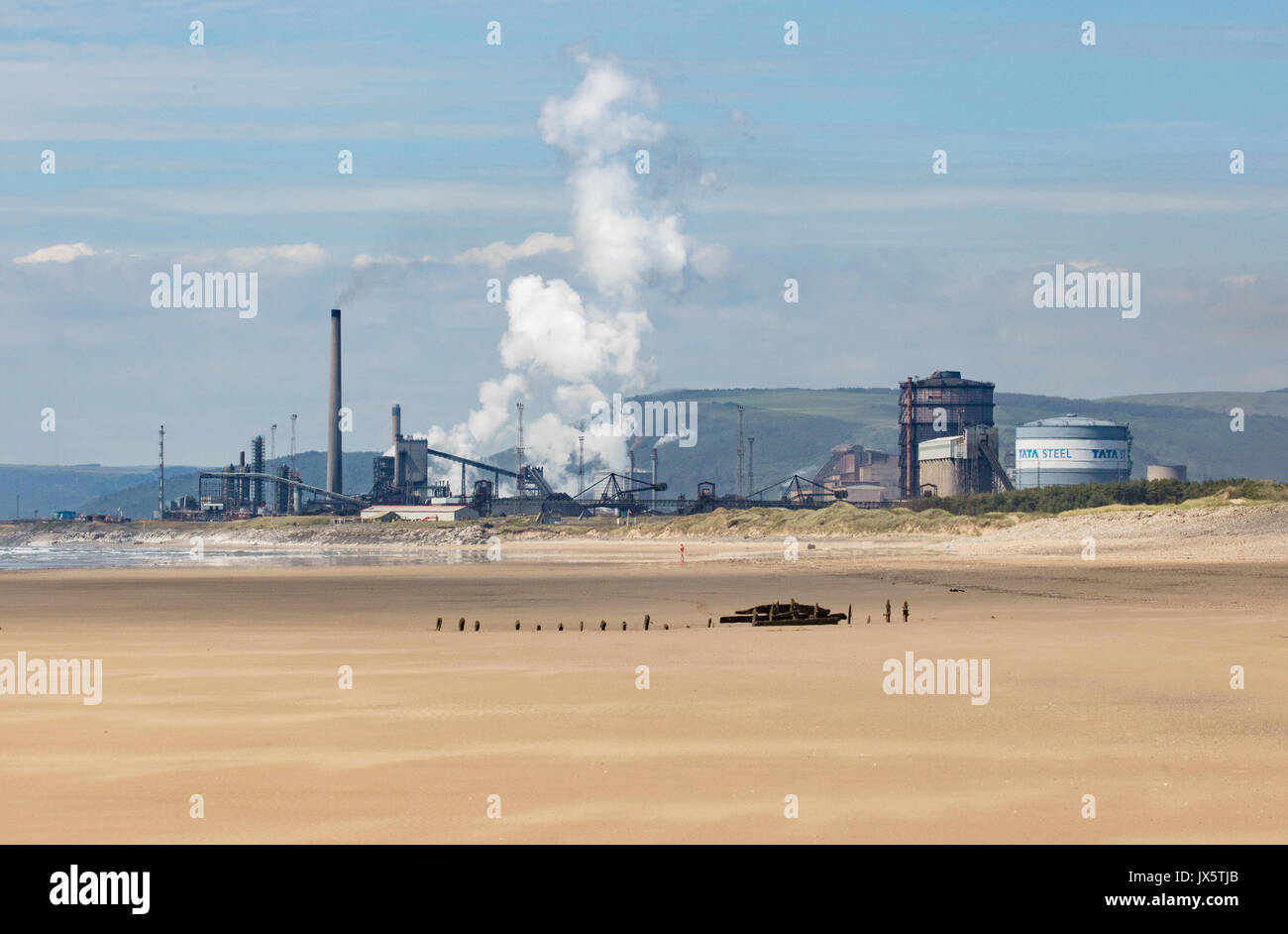 Port Talbot acería propiedad de Tata Steel co de la India visto desde Kenfig madrigueras playa con Naufragio sumergido en primer plano - South Wales UK Foto de stock