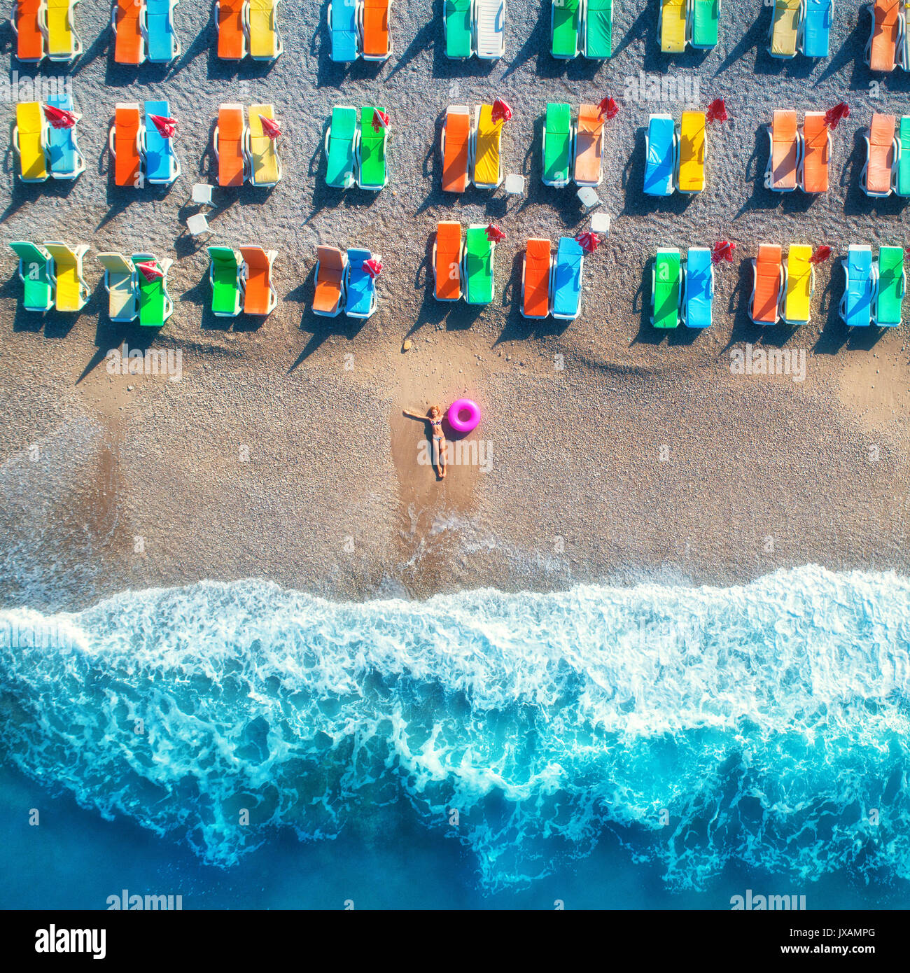 Vista aérea de mentir mujer con anillo de nadar en el mar en Oludeniz, Turquía. Paisaje de verano con la muchacha, aguas turquesa, olas y playas de arena con colorido Foto de stock