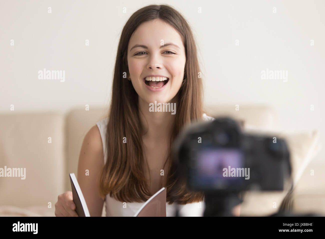 Mujer sonriente positiva hablando a la cámara, la grabación book review Foto de stock