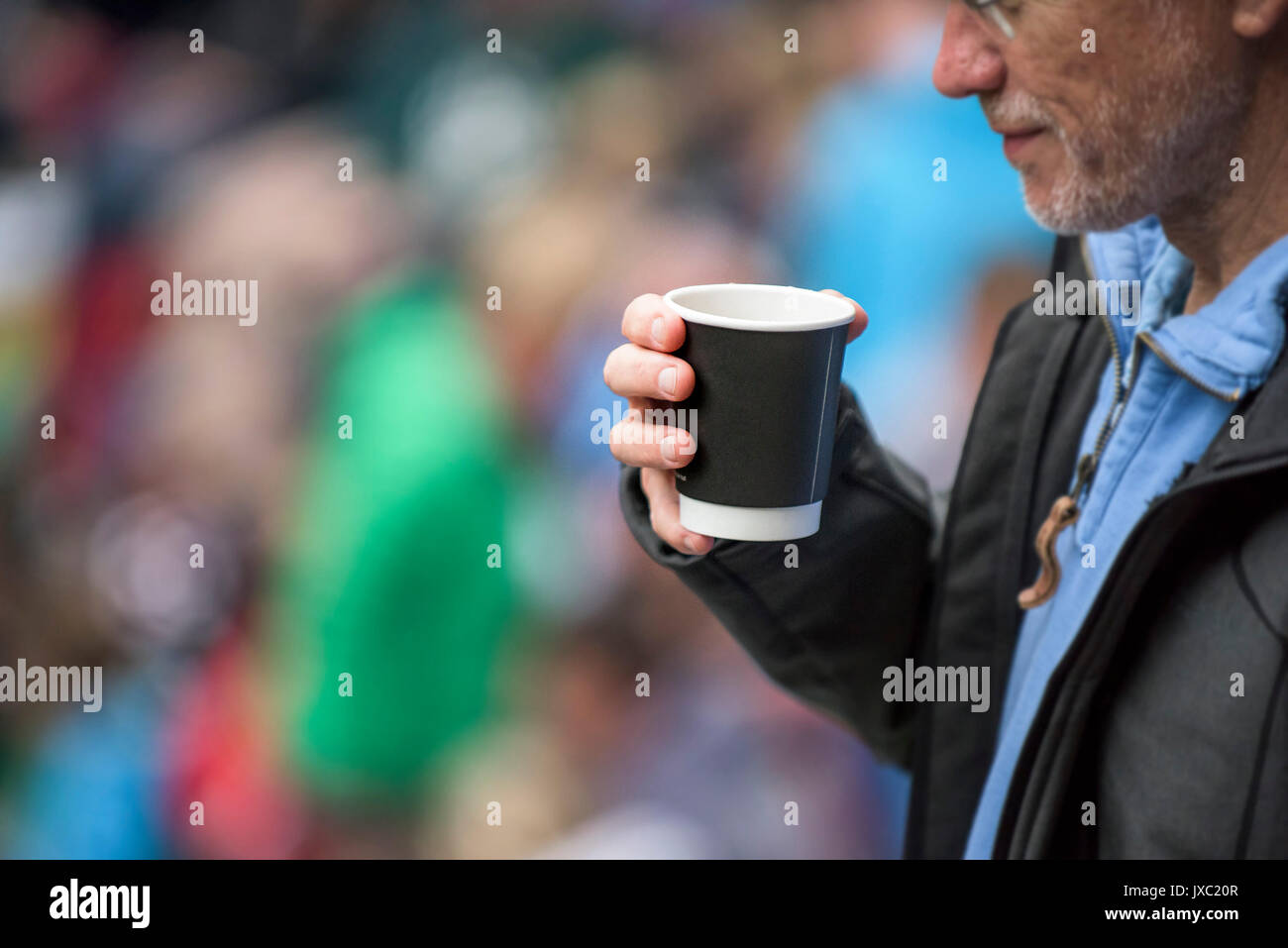 Un hombre bebiendo café fuera de un vaso desechable. Foto de stock