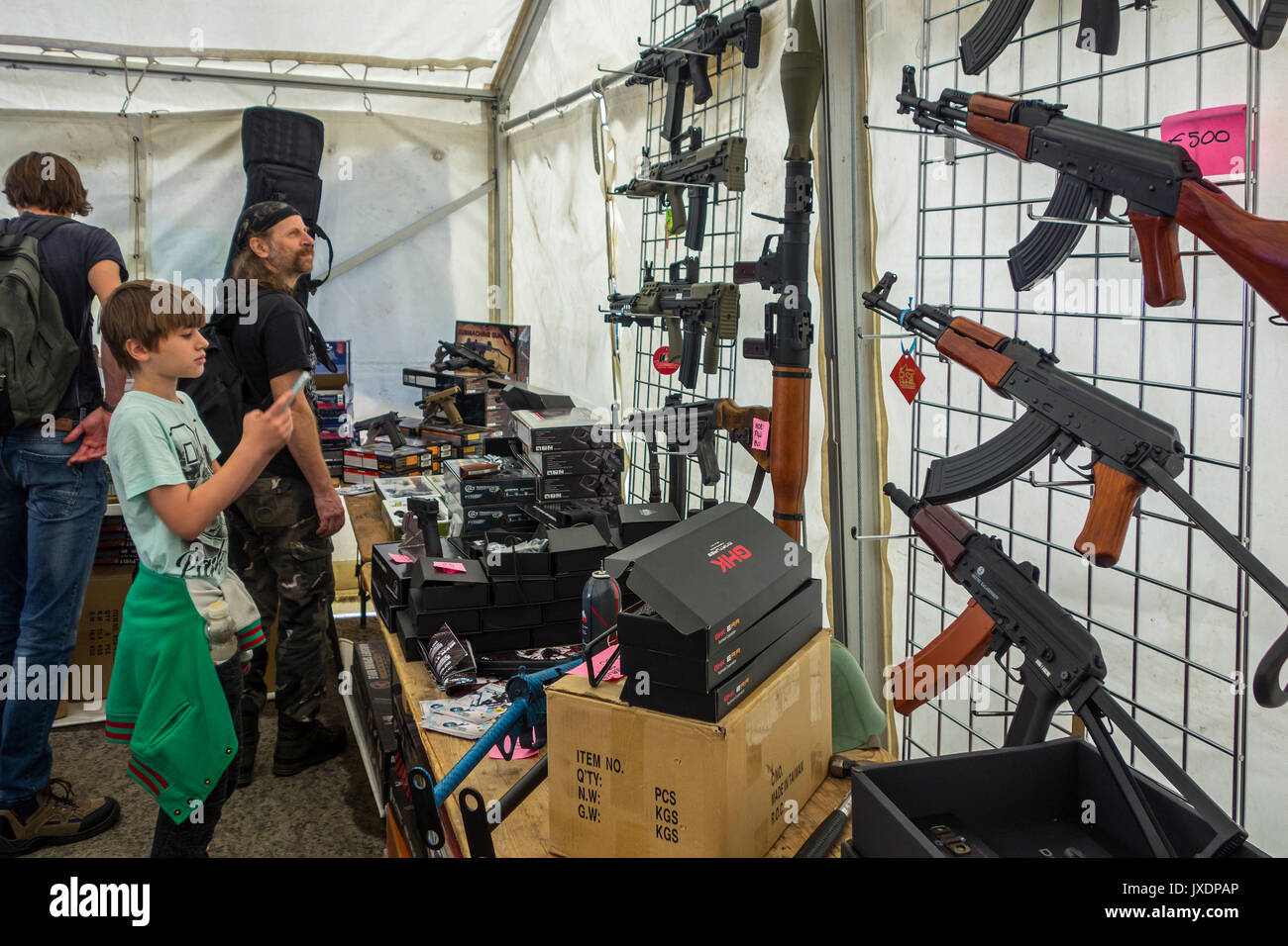 Niño y visitantes que buscan en airsoft pistolas para la venta, réplica de las armas diseñadas para realistas parecen auténticas armas de fuego en la feria militaria Foto de stock