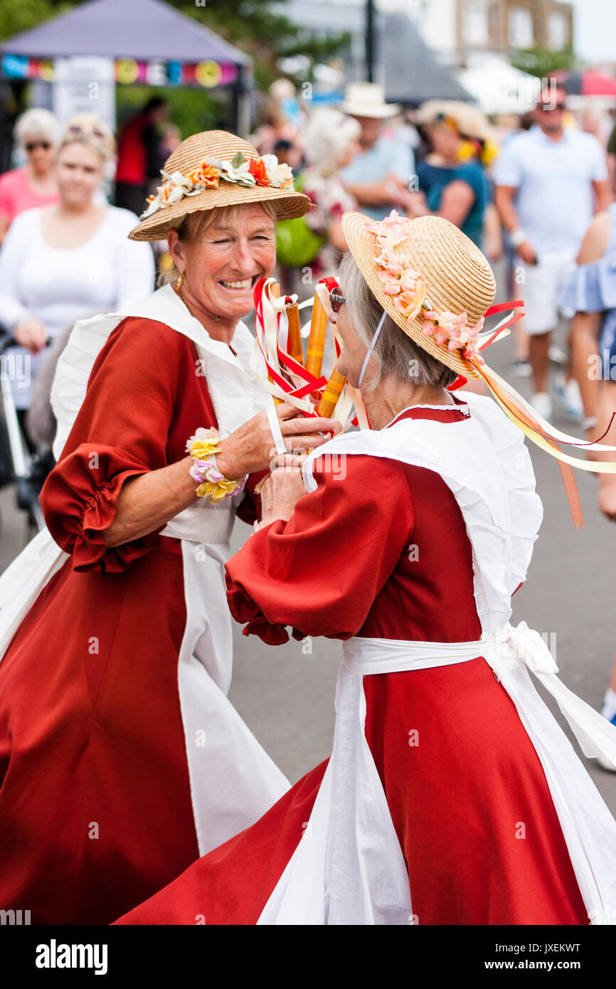 Womens Morris bailarines tradicionales, el aumento de las alondras. Vestidos  de naranja vestidos largos delantales blancos y sombreros de paja. Dos  mujeres maduras sonriente bailando arremolinándose alrededor de cada uno de  los