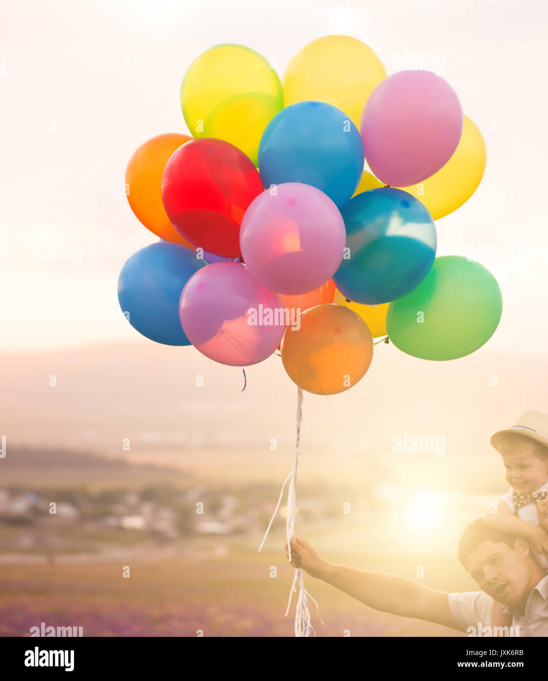 Padre e hijo jugando con balones en campo lila Foto de stock