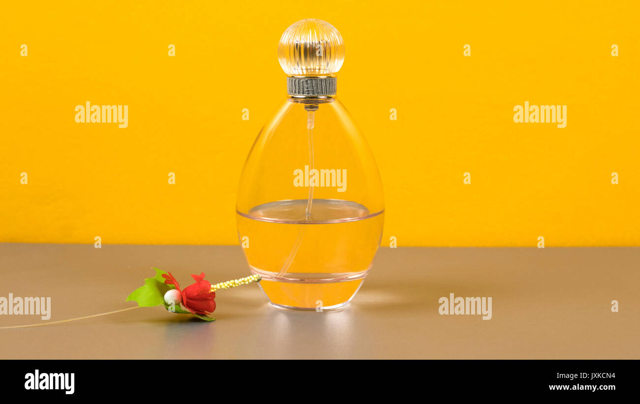 Frasco de perfume de color naranja con una flor Fotografía de stock - Alamy