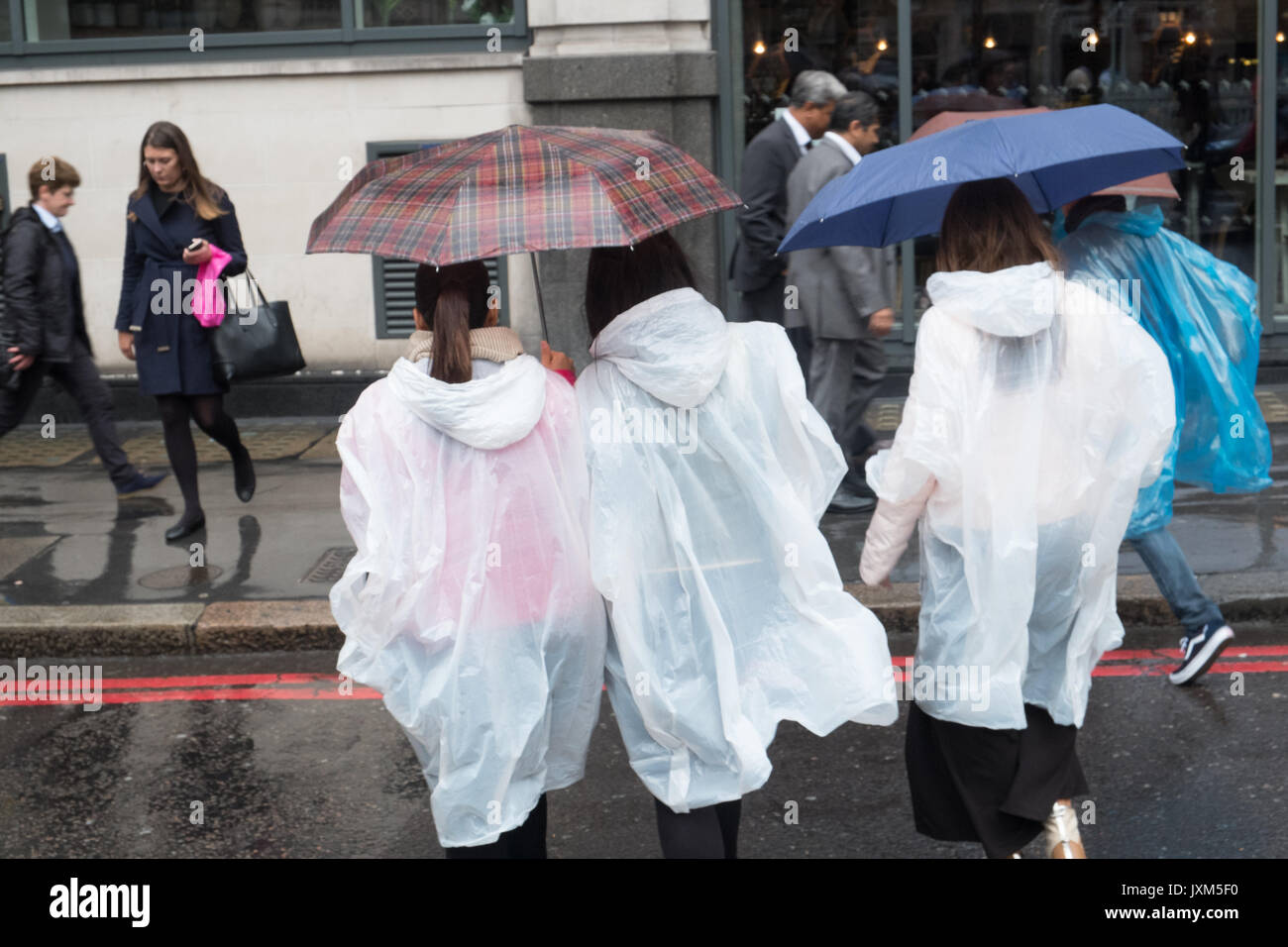 Mujer riendo vistiendo un poncho de plástico durante una ducha de lluvia  Fotografía de stock - Alamy