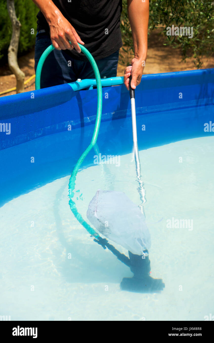 Primer plano de un joven hombre caucásico de limpiar la parte inferior de  una piscina portátil colocado en el patio con un limpiafondos manual  Fotografía de stock - Alamy