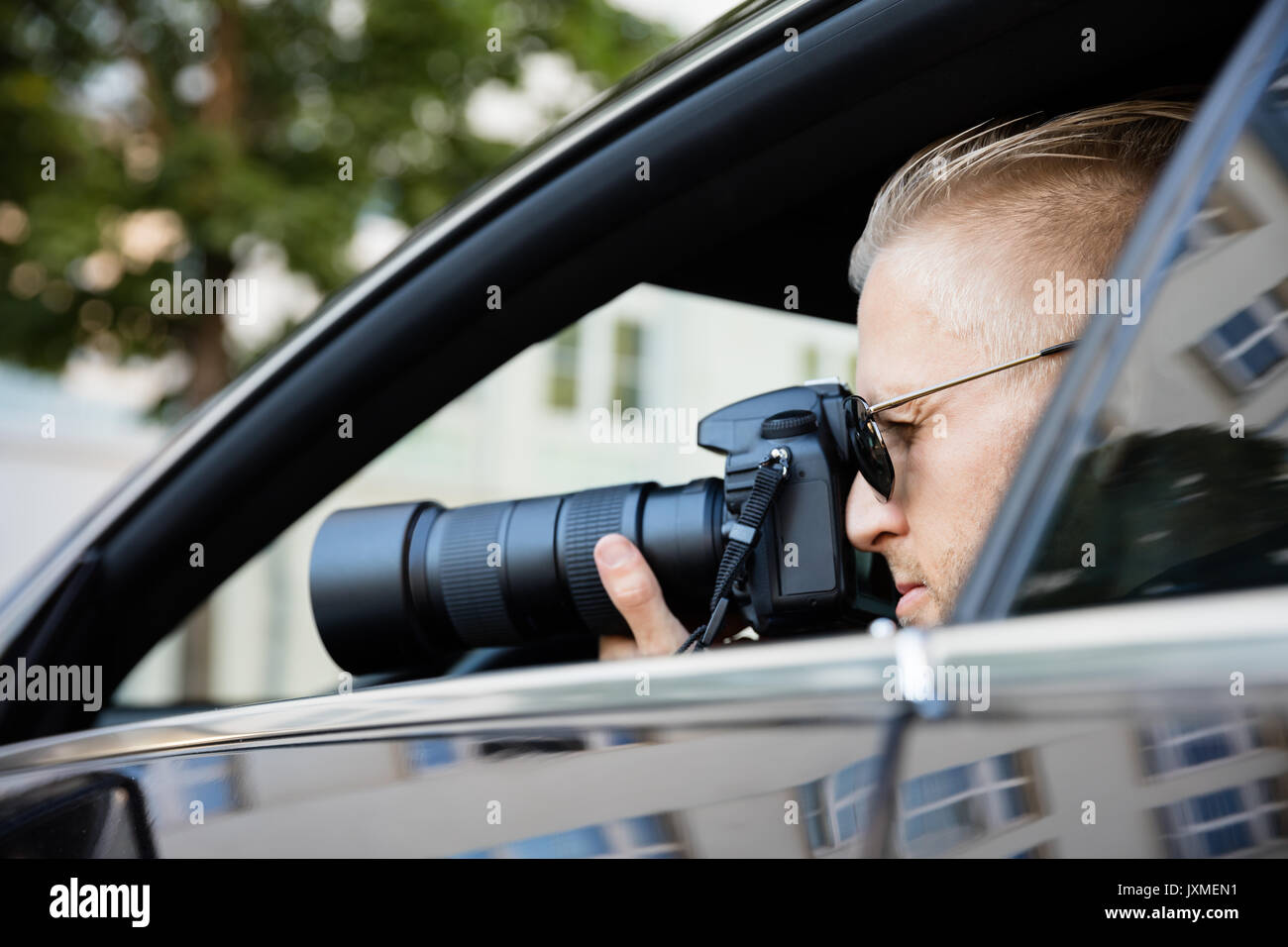Paparazzi sentados dentro del coche fotografiar con cámara réflex digital Foto de stock