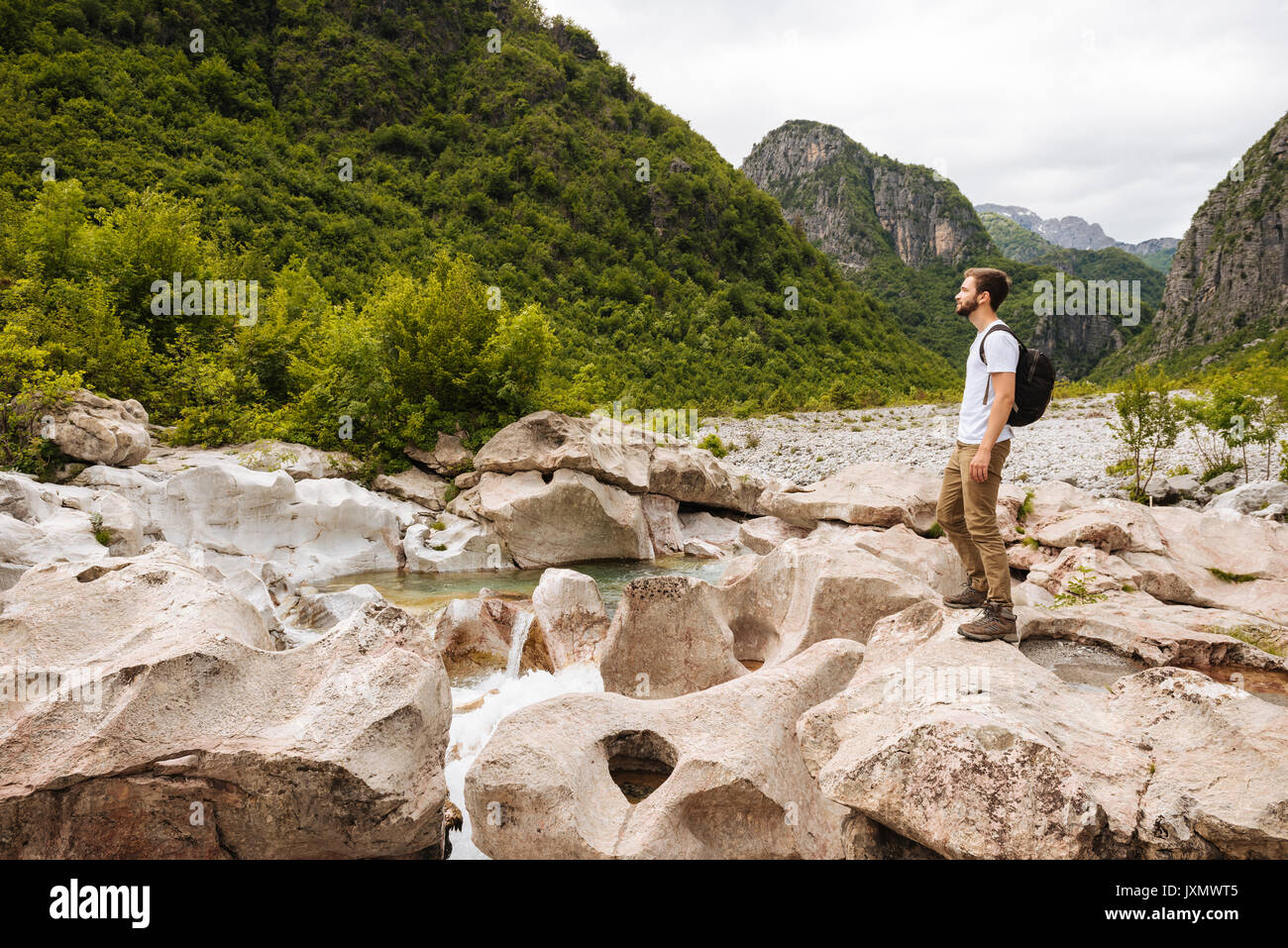 Hombre de pie en las rocas mirando lejos, montañas, maldito Theth, Shkoder, Albania, Europa Foto de stock