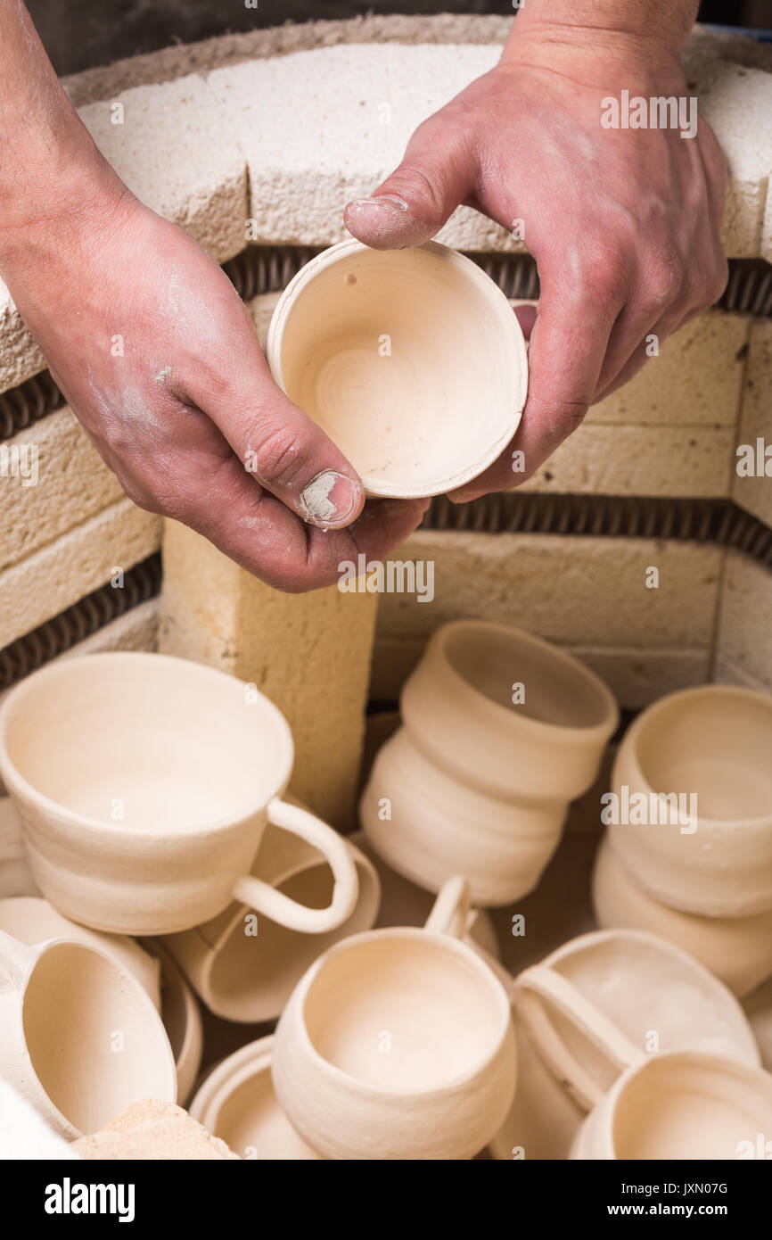 Taller de alfarería, cerámica, concepto de arte - macho manos colocando  suavemente la jarra en el horno, vista superior del horno de calcinación de  los productos de arcilla sin horneado, algunos vasos