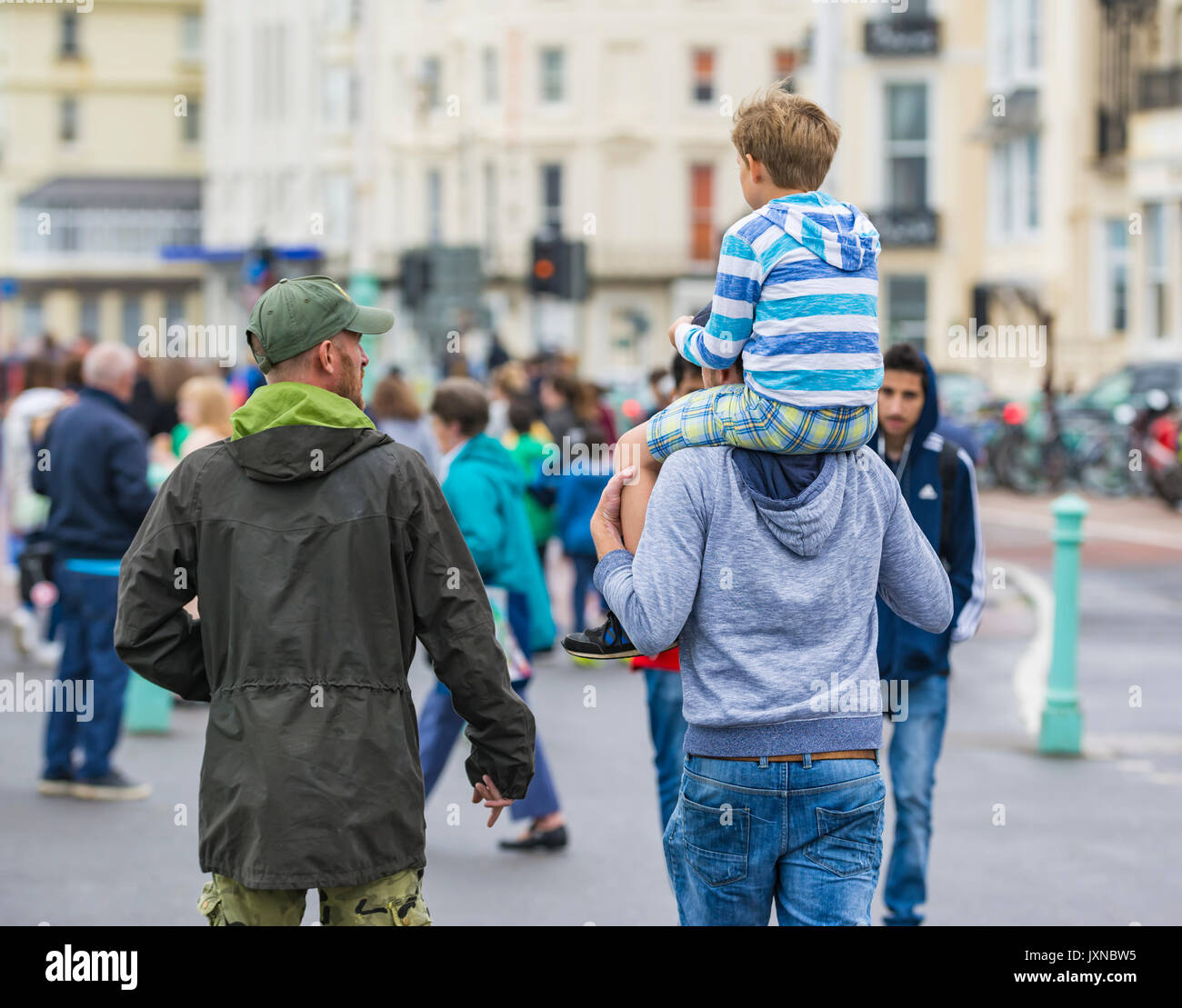 Hombre en una ajetreada ciudad llevando un niño sobre sus hombros. Foto de stock