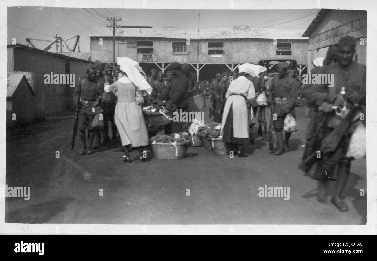 Dos mujeres están dando a los hombres afroamericanos bolsas pequeñas, 1929. Foto de stock