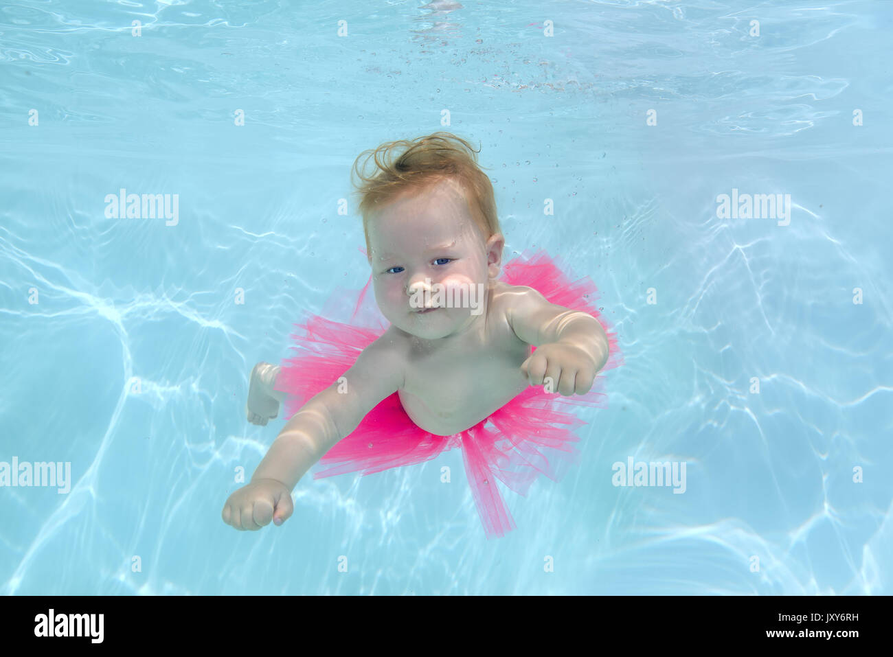 Niña pelirroja en una falda rosa nadar bajo el agua en la piscina  Fotografía de stock - Alamy