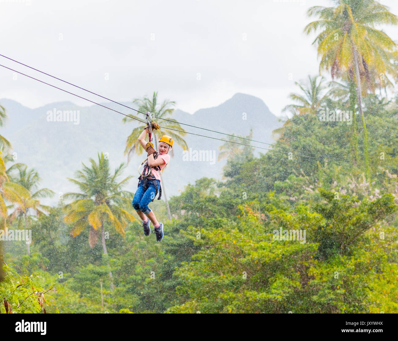 Chica caucásica colgando de canopy en el bosque Foto de stock