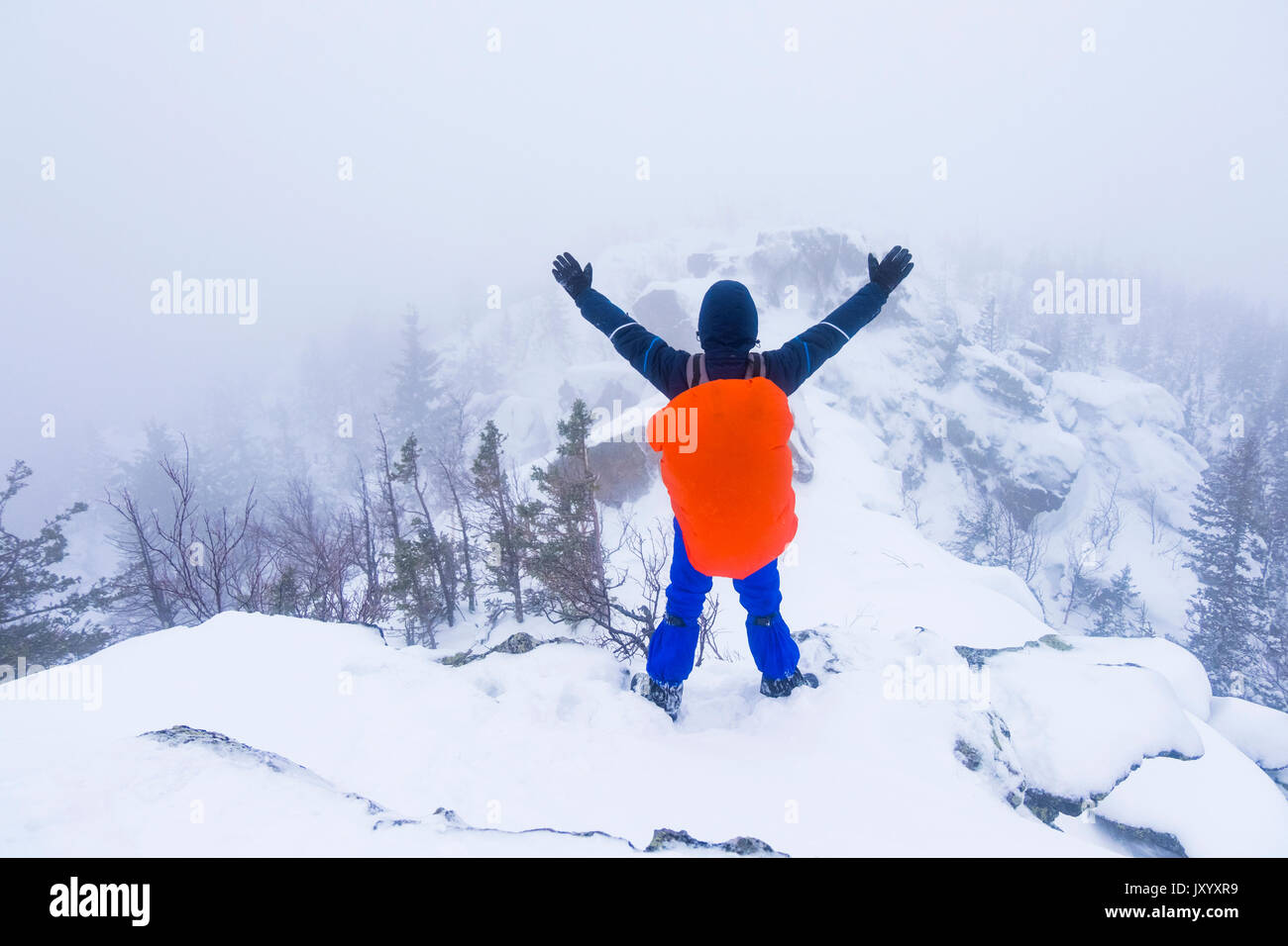 Excursionista caucásica ondeando en montañas cubiertos de nieve Foto de stock