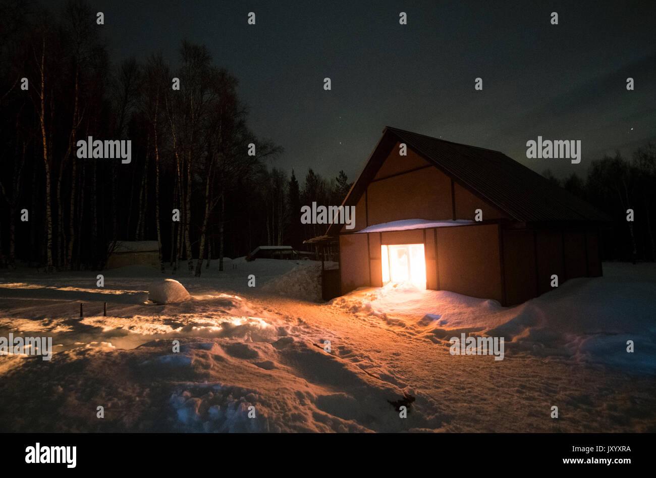Luz brillando en el granero remoto en invierno Foto de stock