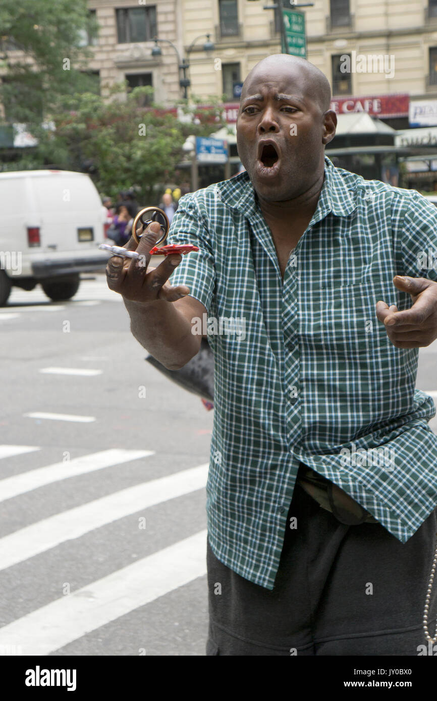 Un hombre expresivo vendiendo molestar spinners demuestra spinning varios de ellos en uno. En la sección de Herald Square de Manhattan, Ciudad de Nueva York. Foto de stock