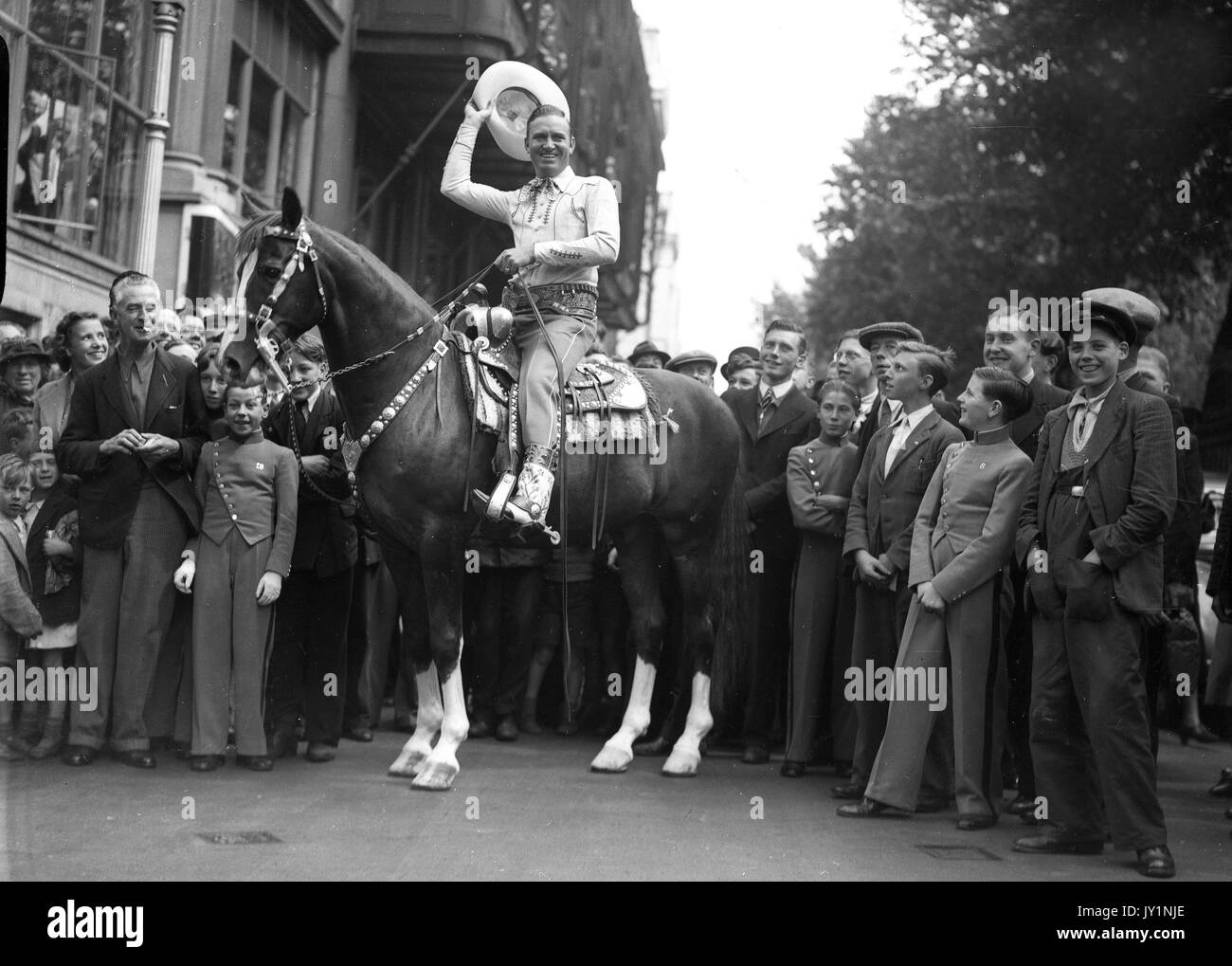 Gene Autry Hollywood's Singing Cowboy a caballo campeón rodeado por multitudes de jóvenes en la emperatriz Hall Julio de 1953 Foto de stock