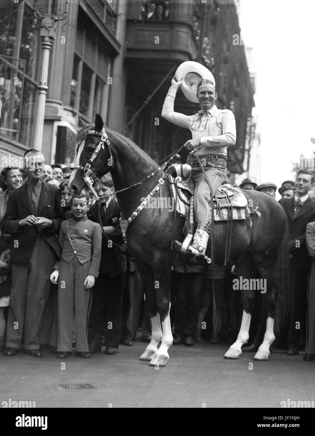 Gene Autry Hollywood's Singing Cowboy a caballo campeón rodeado por multitudes de jóvenes en la emperatriz Hall Julio de 1953 Foto de stock