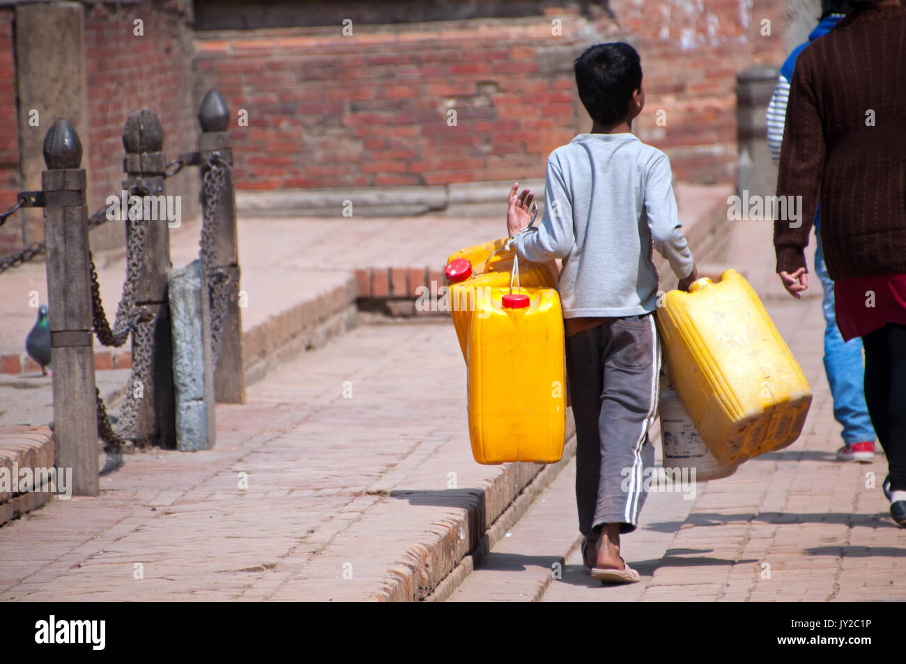 Katmandú, Nepal - Marzo 9, 2013: el joven niño sosteniendo un galón recipiente para recoger agua limpia en el grifo público en el valle de Katmandú. Foto de stock