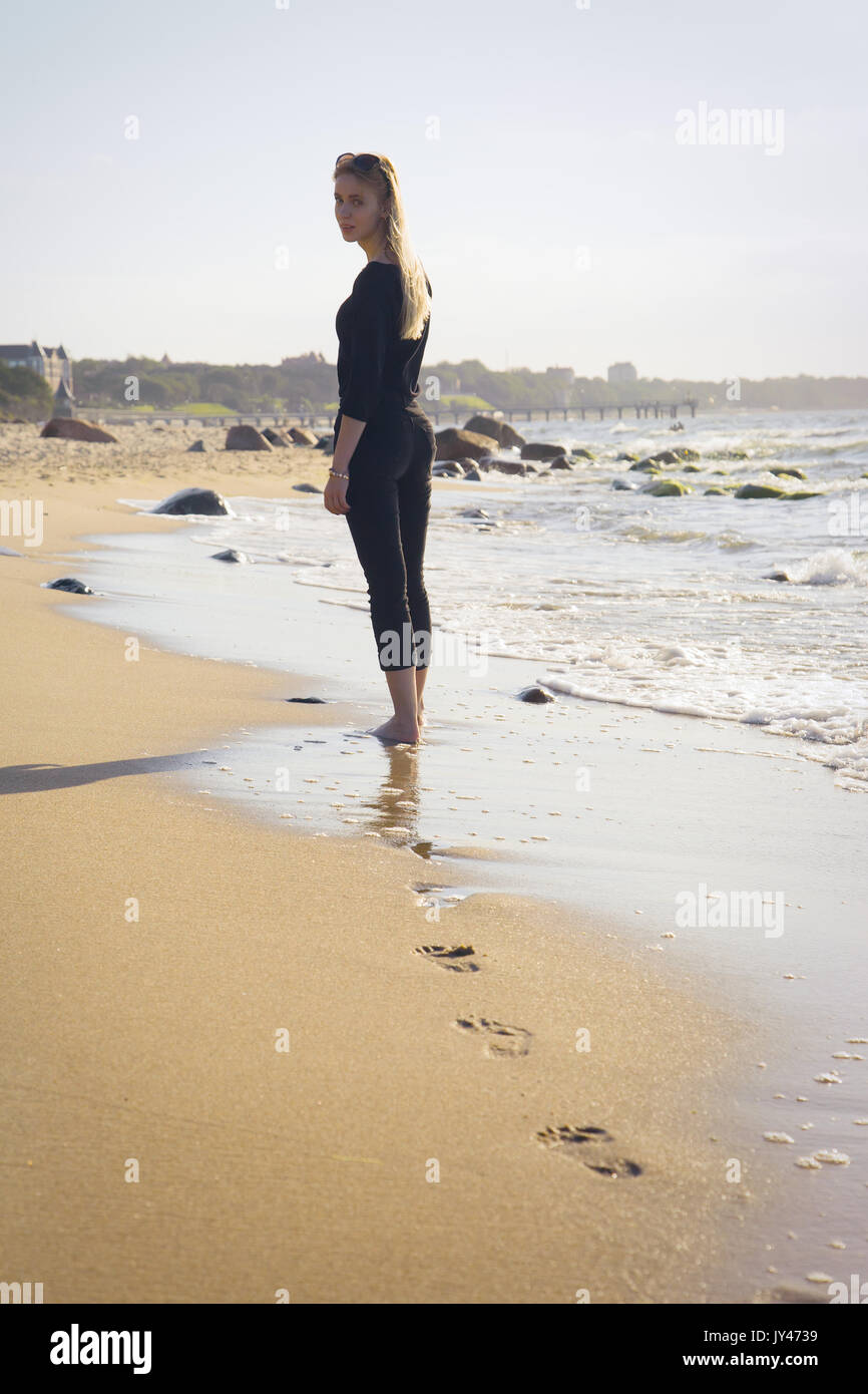 Triste rubia mujer desnuda mirando hacia atrás en la soleada playa de mar  Fotografía de stock - Alamy