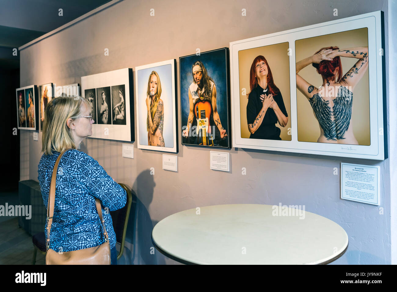 Mujer viendo Gicleé impresiones fotográficas de gente tatuada; Paquette Galería; SteamPlant Event Center; Salida, Colorado, EE.UU. Foto de stock