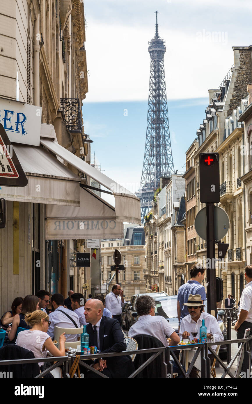 Fuera Cafe diners disfrute del cálido verano contra un telón de fondo de la torre Eiffel París Francia Foto de stock