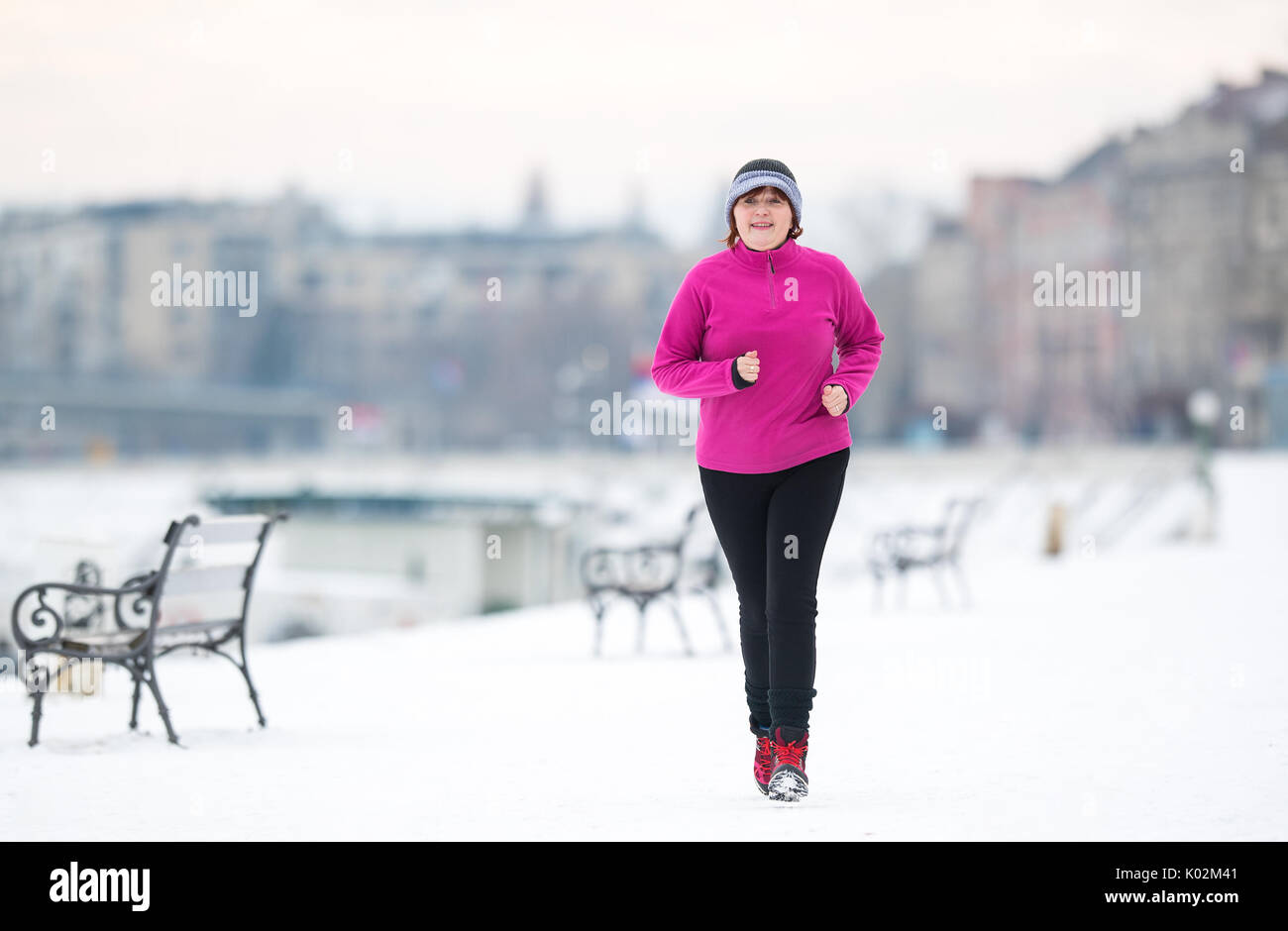 Mujer de edad, vistiendo ropa deportiva y correr sobre la nieve durante el  invierno Fotografía de stock - Alamy