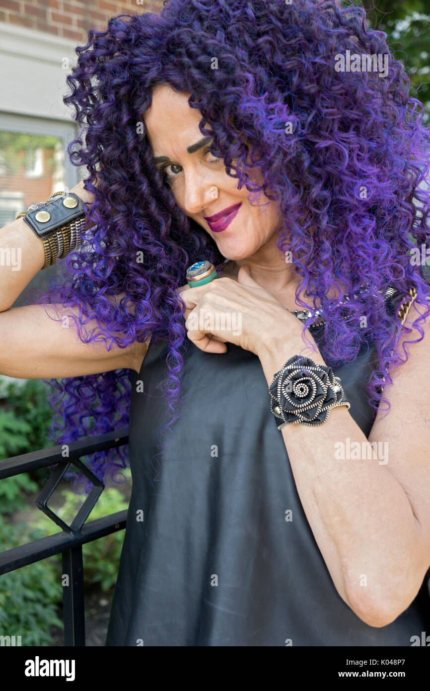 Una mujer de casi cincuenta años busca joven con largo cabello rizado púrpura y un atuendo de verano en Greenwich Village, Nueva York. Foto de stock