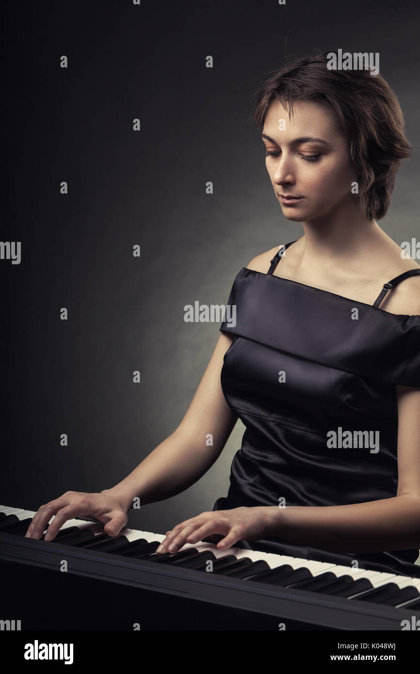 Bella mujer tocando el piano en un fondo negro Fotografía de stock - Alamy