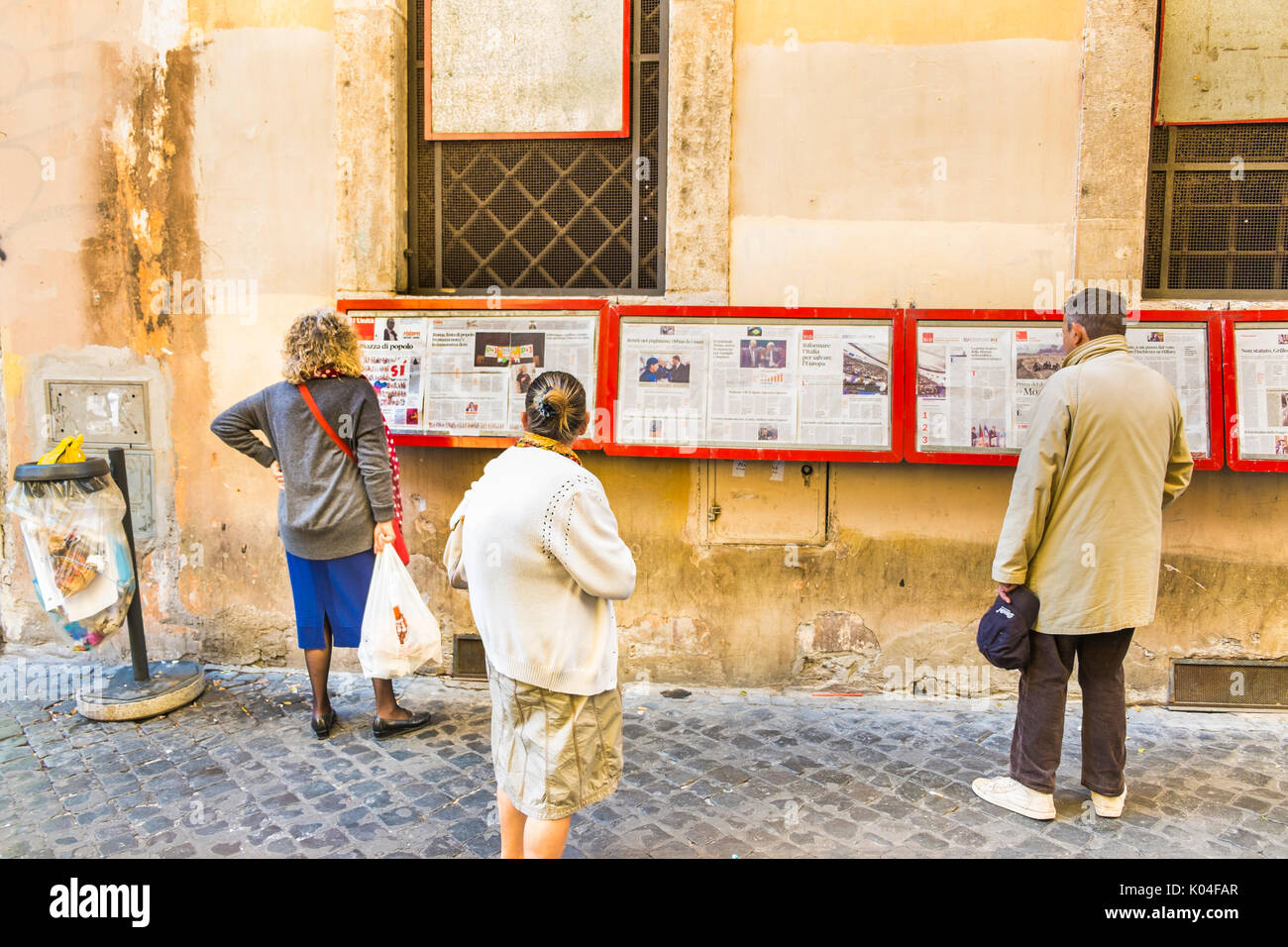 Personas leyendo l'Unita, prensa diaria en la pantalla fuera de la sección pci local en el centro histórico de la ciudad de Roma. Foto de stock