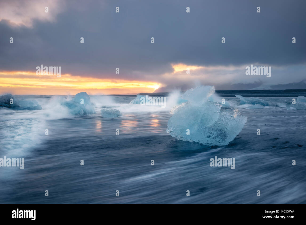 Bloque de hielo en la playa negra en la Laguna glaciar Jokulsarlon durante una puesta de sol, el este de Islandia, Europa Foto de stock