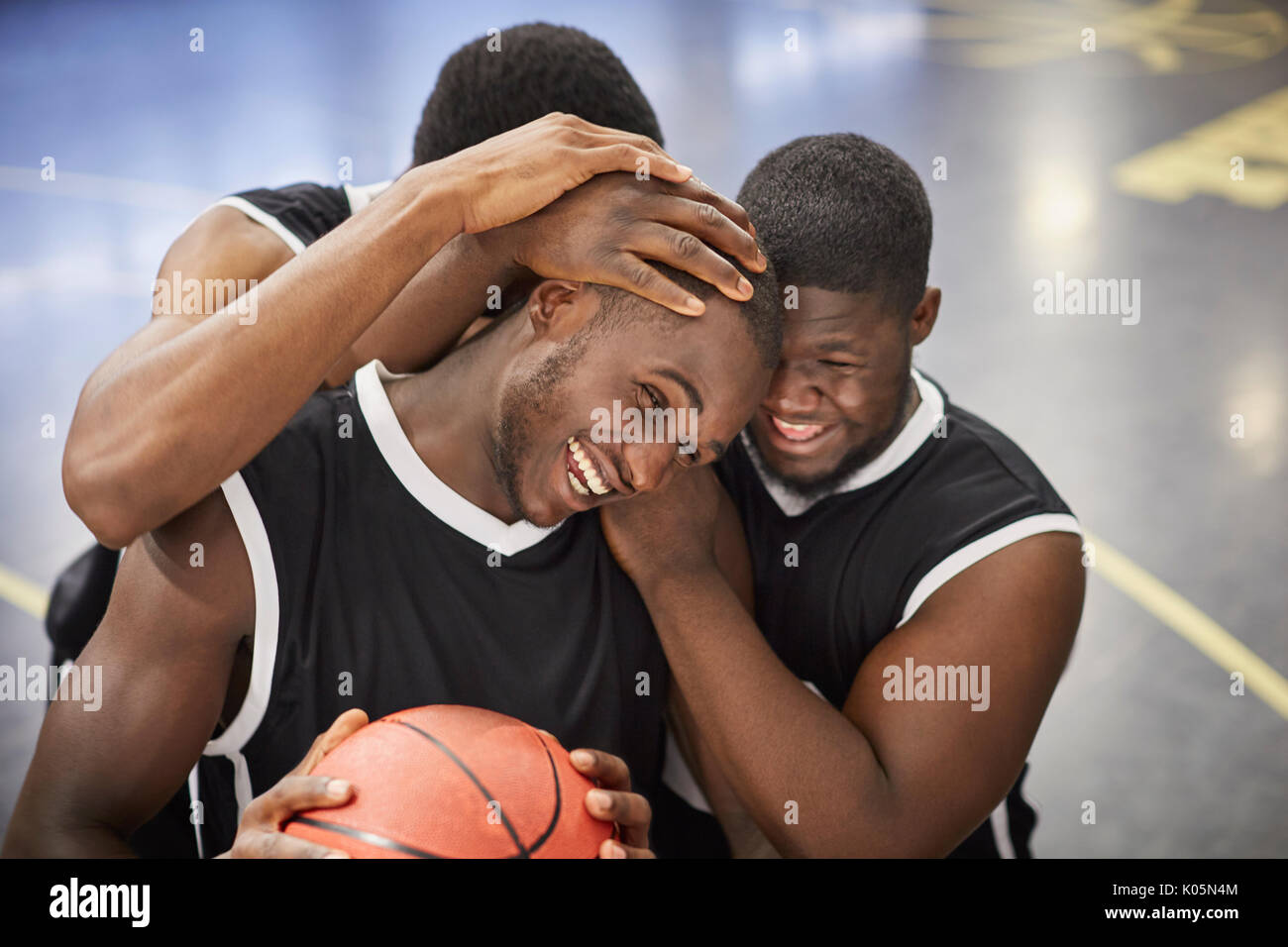 Felices los jóvenes jugadores de baloncesto masculino abrazando y celebrando después de la victoria Foto de stock