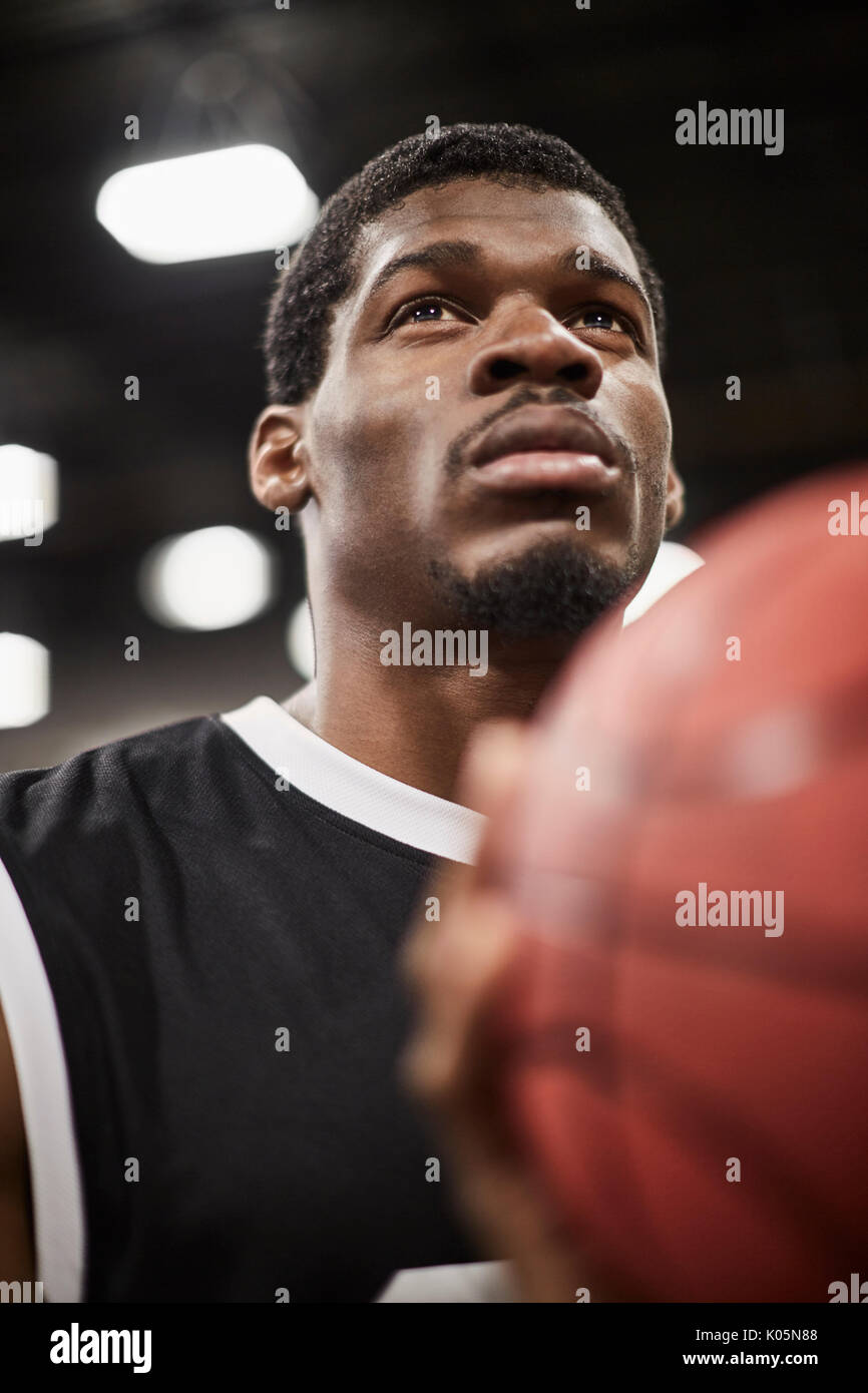 Cerrar retrato serio, centrado joven jugador de baloncesto masculino lanzando la bola Foto de stock